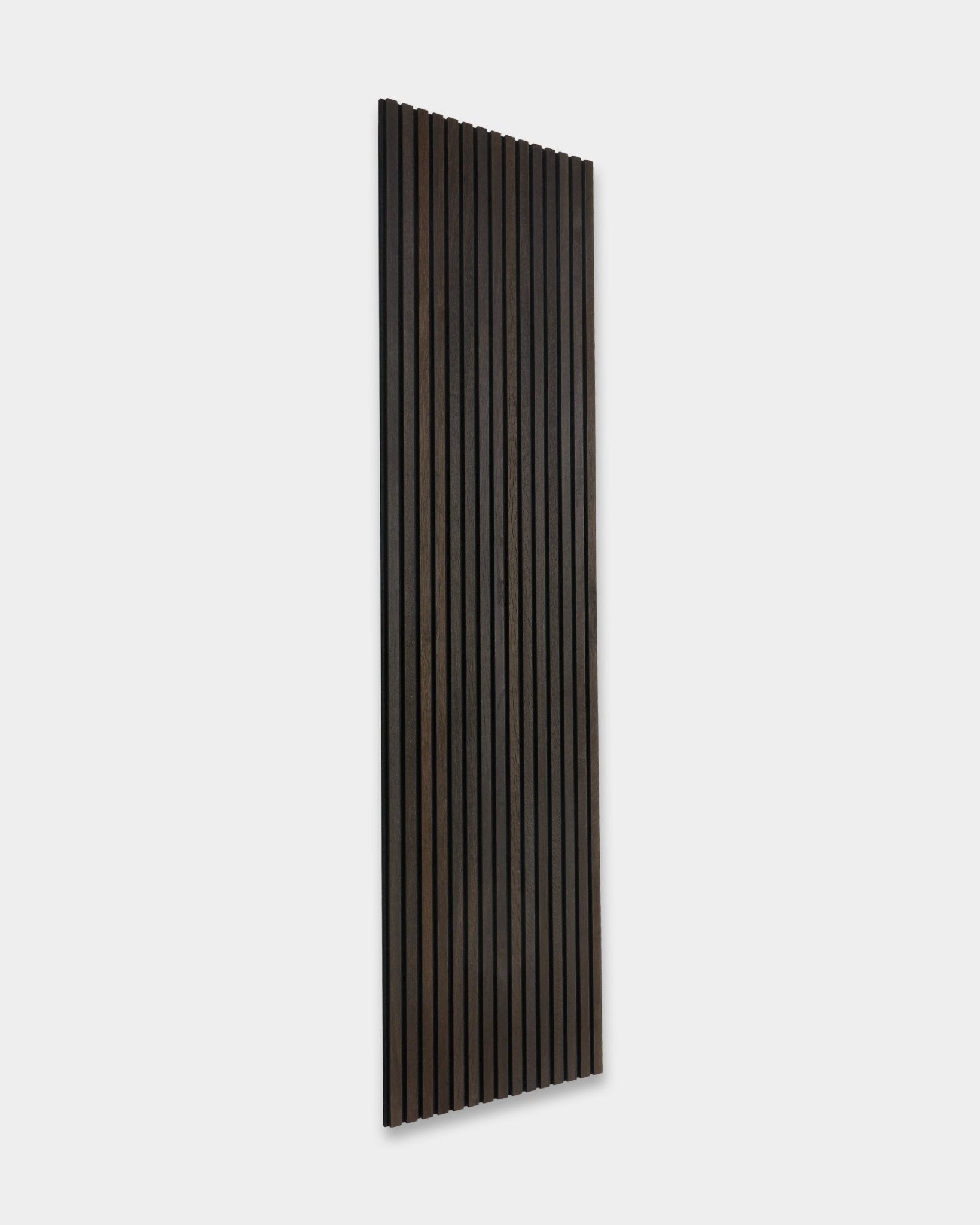 Rustic Smoked Oak Akupanel Akustikkpanel fra WoodUpp, med vertical mørke trespiler, lent mot en lys grå vegg.