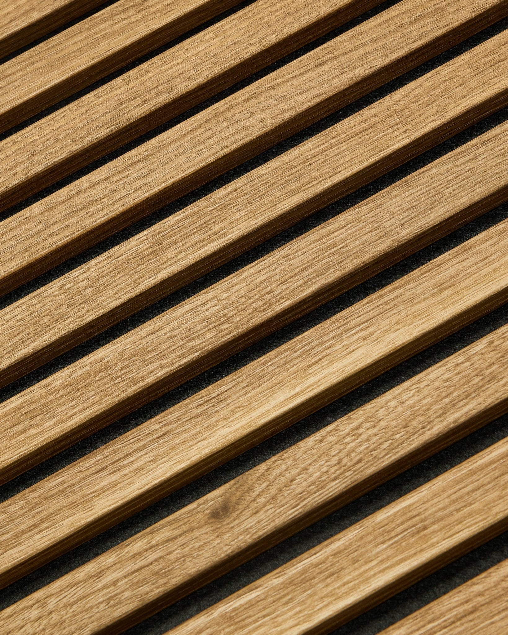 Essential Akupanel Akustikkpanel i English Oak fra WoodUpp, 240 x 60 cm, med jevnt fordelte diagonale spiler mot en mørk bakgrunn.