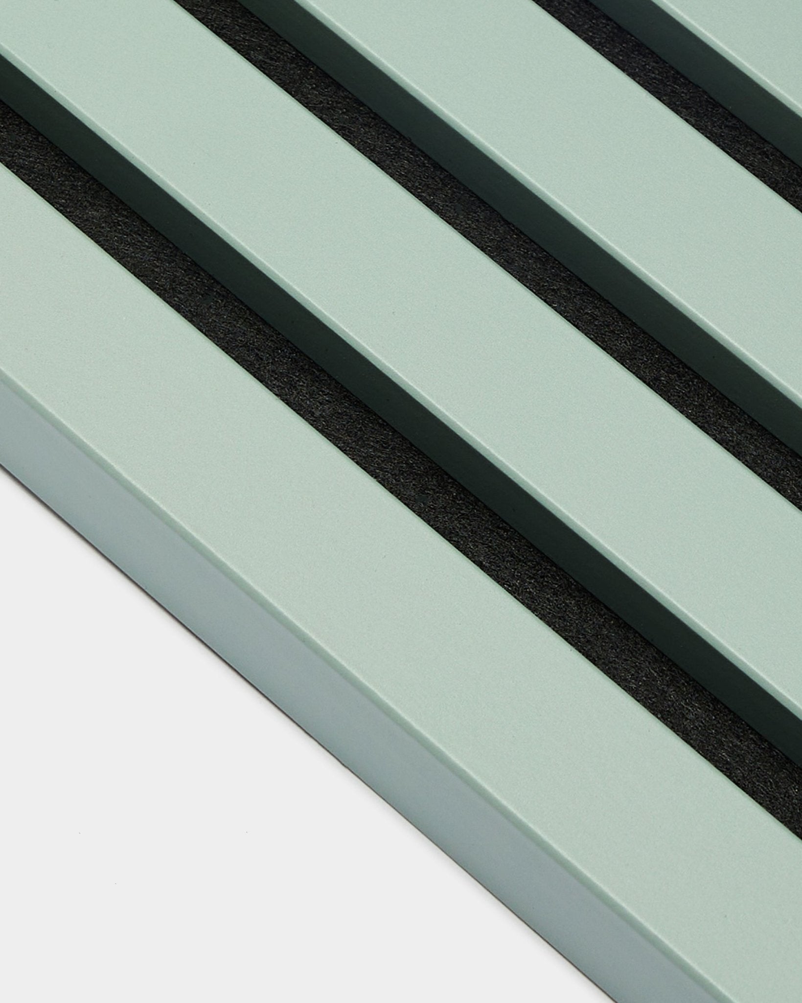 Nærbilde av tre parallelle pastellgrønne End Lamella / Cloud-lameller, 2,2 cm brede, fra WoodUpp, som del av en Akupanel Akustikkpanel mot en lys bakgrunn.