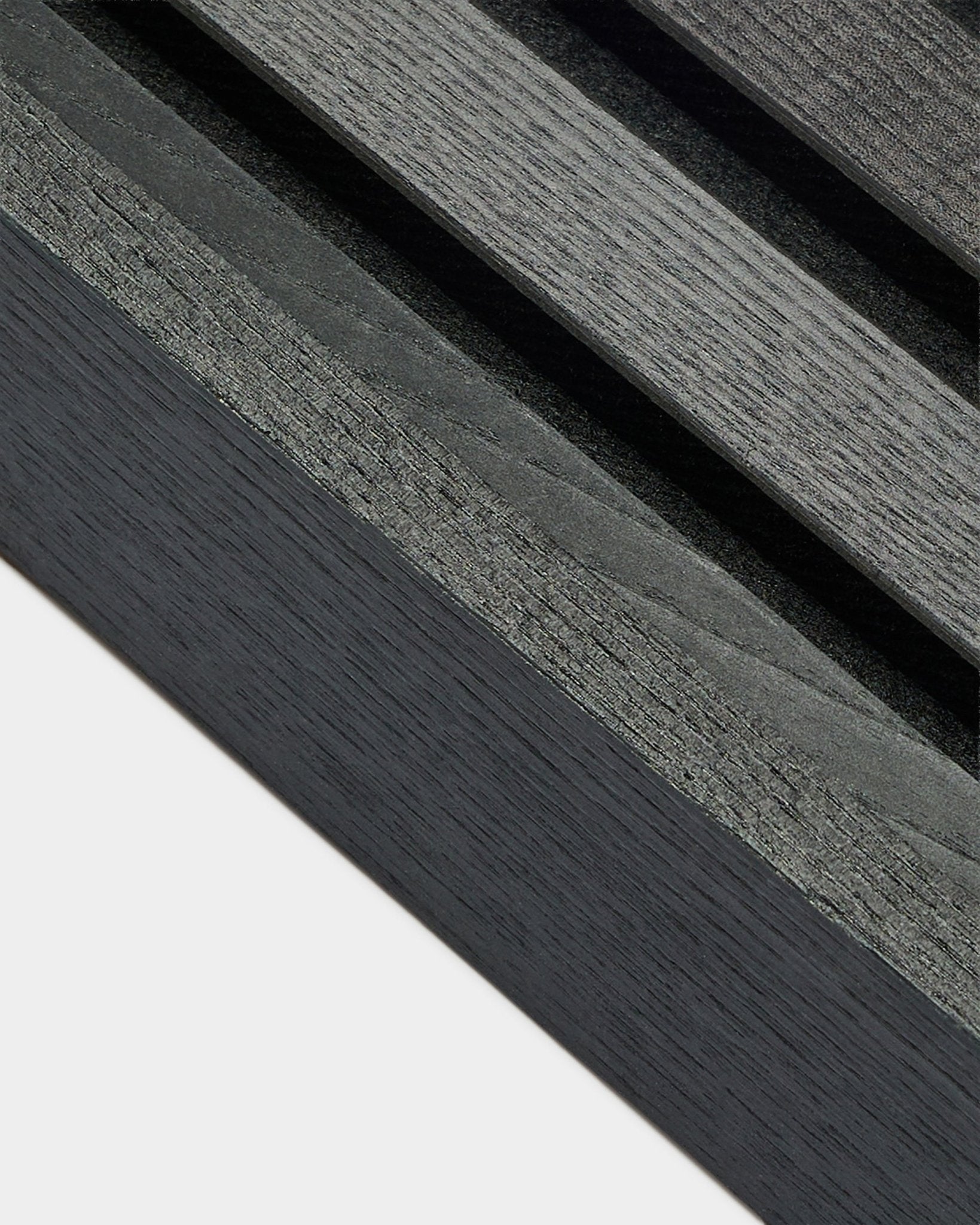 Nærbilde av WoodUpp Akupanel endelamell i Black ask (6,7 cm), som viser mørkegrå årringer på en lys base, utviklet for nordiske Akustikkpanel installasjoner.