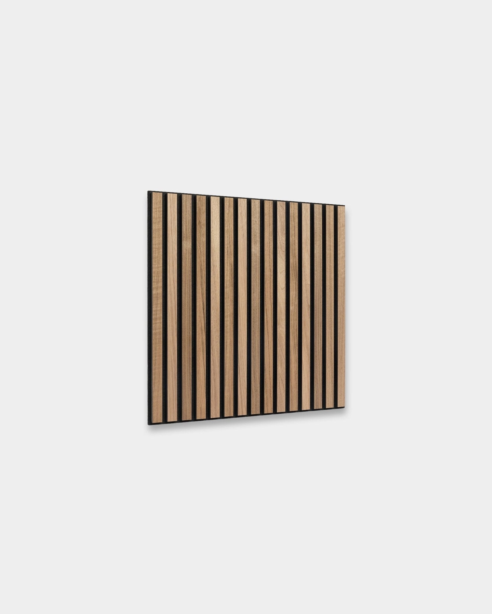 WoodUpp Akupixel Akustikkpanel i valnøtt, 60x60 cm, har jevnt fordelte valnøttspiler med black mellomrom montert på en lys grå vegg for et skandinavisk uttrykk.
