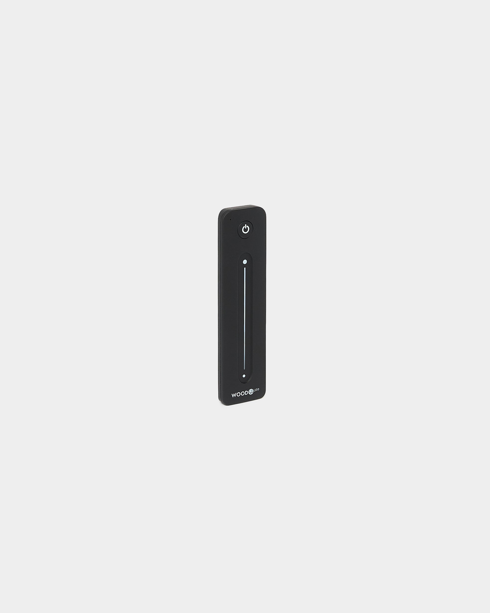 Slank black WoodUpp Lumi fjernkontroll for LED-lysstriper, med vertical berøringsslider og av/på-knapp, kompatibel med Philips Hue, vist mot hvit bakgrunn.