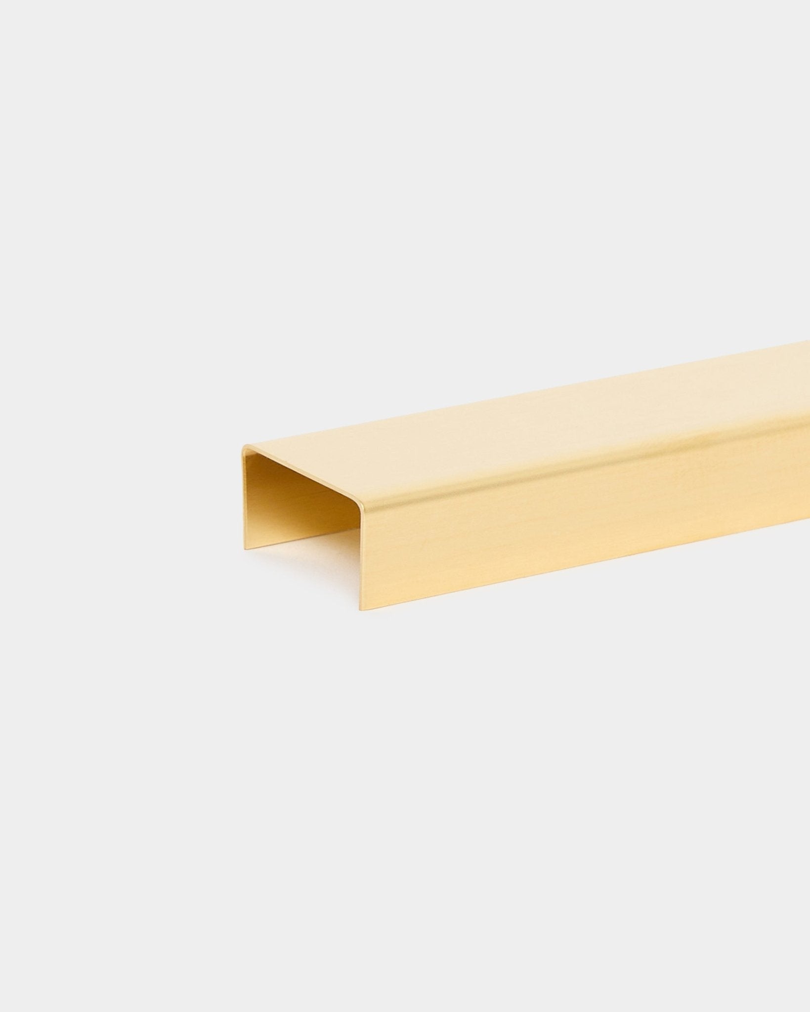 Liva | Cover i brass, 60 cm fra WoodUpp er et U-formet metallist-tilbehør for Akupanel akustikkpaneler, vist mot en ensfarget lys grå bakgrunn.