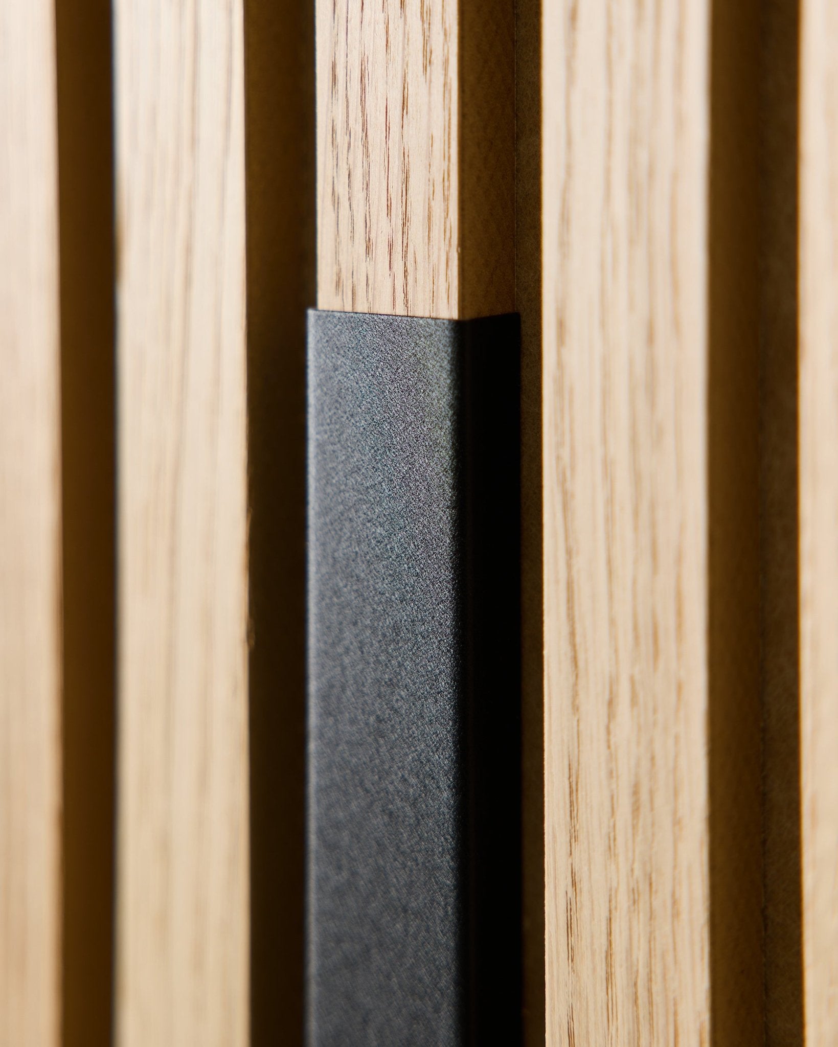 Nærbilde av WoodUpp Liva Akustikkpanel med 60 cm black aluminiumsdeksel, som viser vertical trespiler og en black detalj for moderne, nordiske interiører.