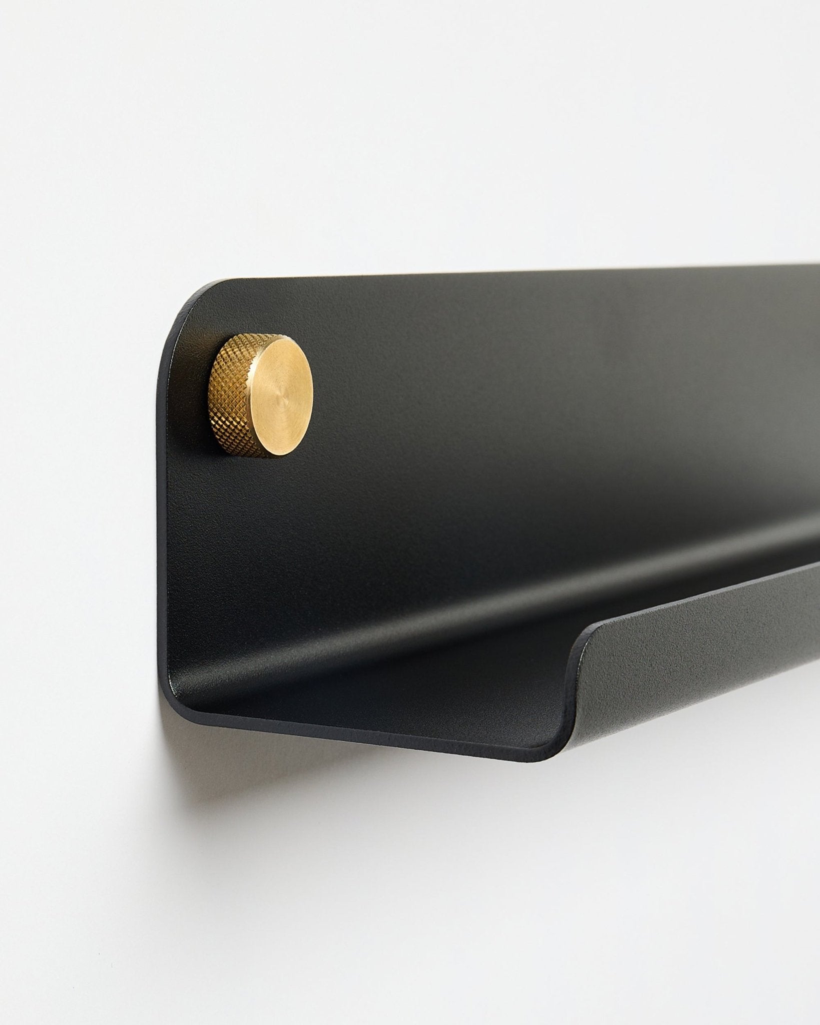 Norr | Smal hylle i black (115,9 cm) med én gullknott på venstre side, fra WoodUpp, montert på en enkel hvit vegg.