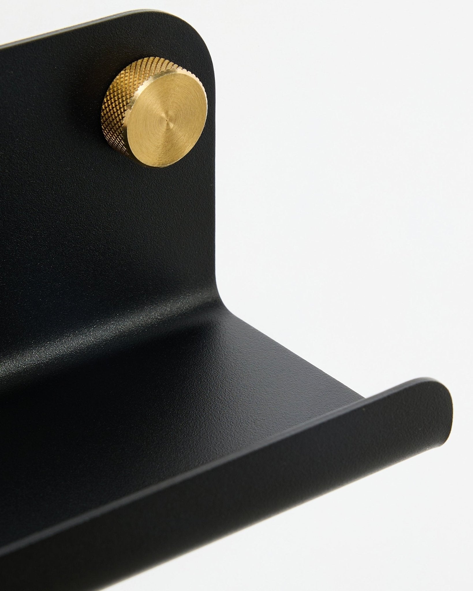 Nærbilde av WoodUpp Norr smal hylle, 35,9 cm, black steel med buet kant og gullfarget knott, vist mot en hvit bakgrunn.
