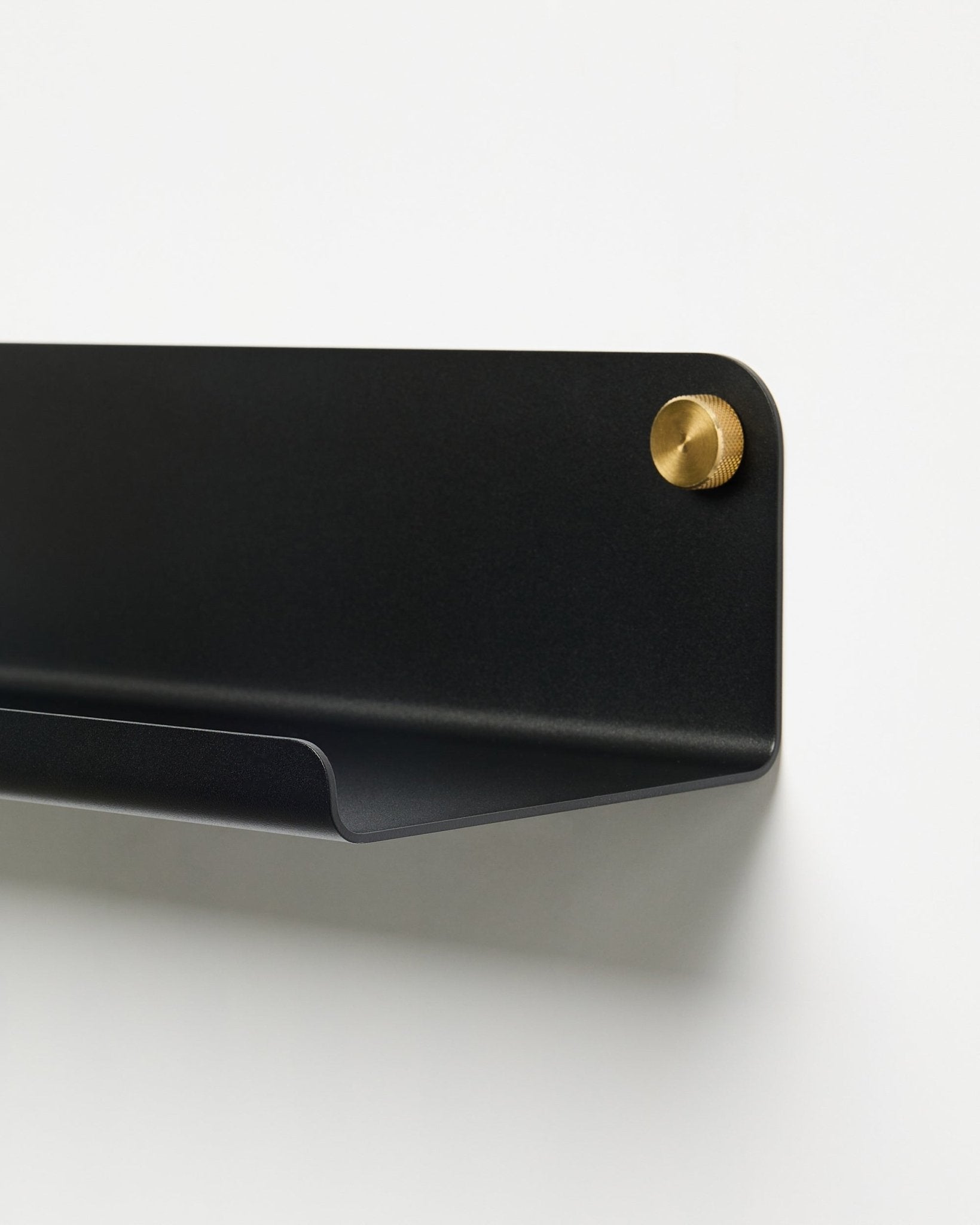 Nærbilde av WoodUpp Norr Wide Shelf-tilbehøret (51,9 cm) i pulverlakkert black metall med gullskrue, plassert mot en enkel hvit bakgrunn.