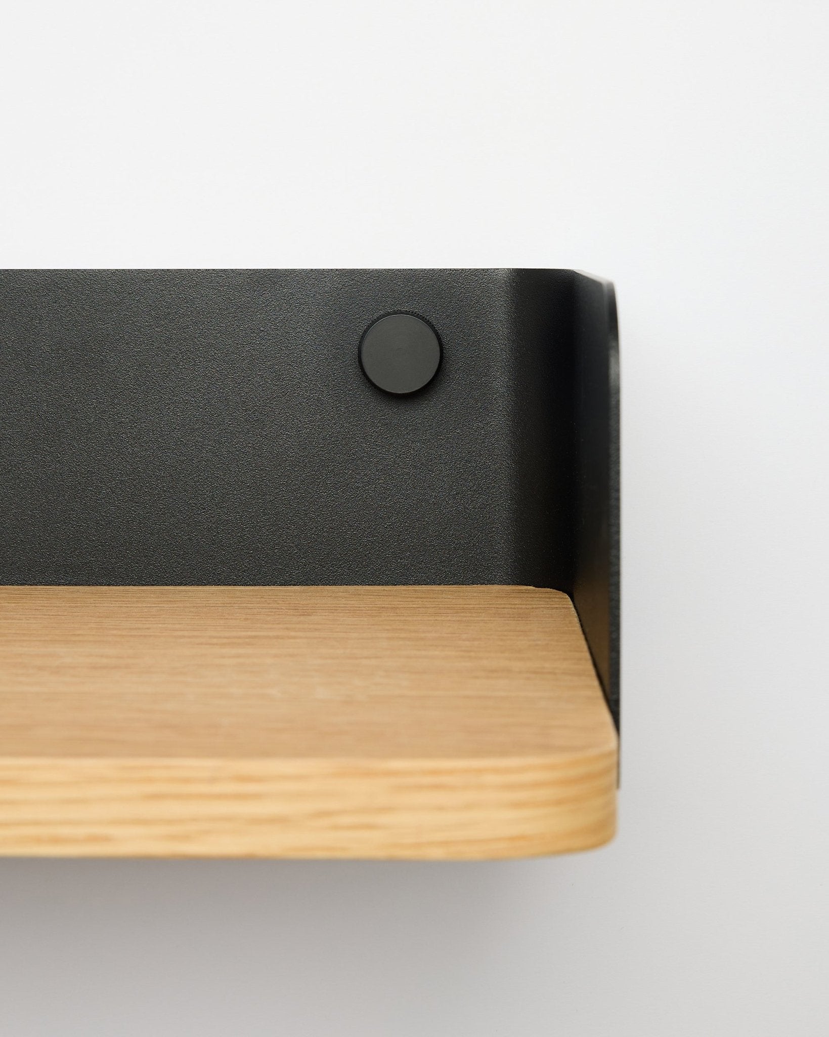 Linn Bookshelf fra WoodUpp i natural oak, 55,9 cm bred, med black metallbrakett, montert på en hvit vegg; nærbilde fra høyre side.