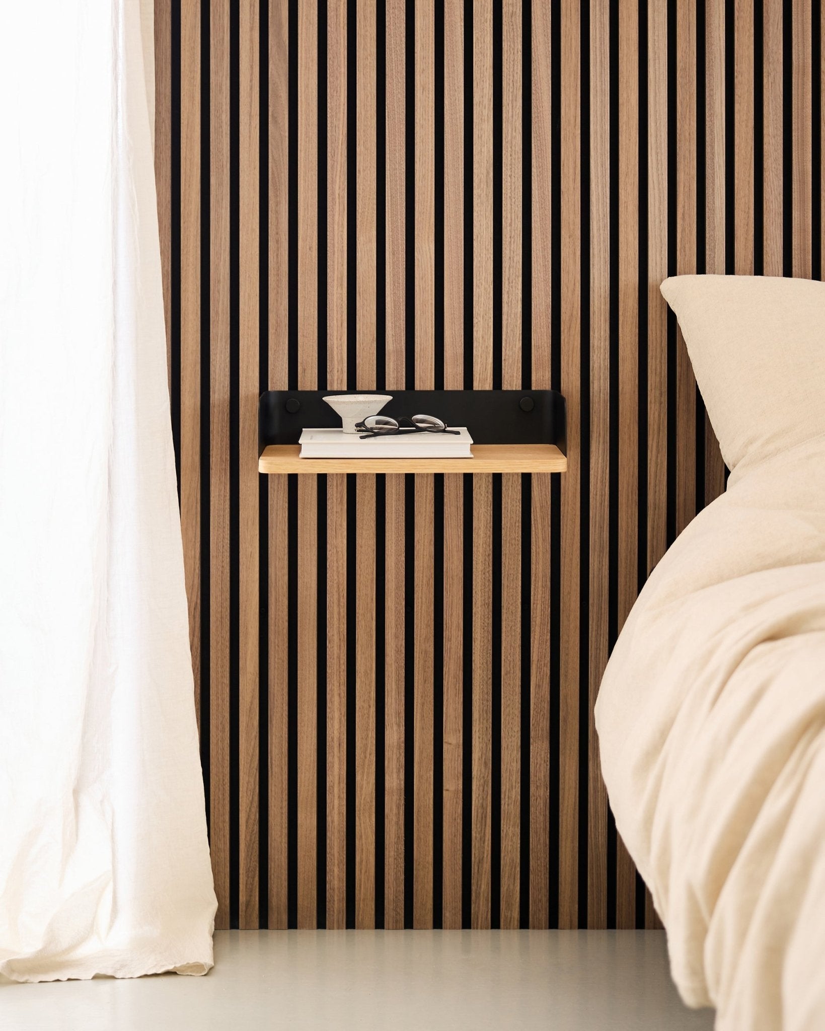 Minimalistisk soverom med en nordisk trelamellvegg Akustikkpanel, WoodUpp Linn Bookshelf i Natural Oak, og et svevende nattbord ved siden av en beige seng.