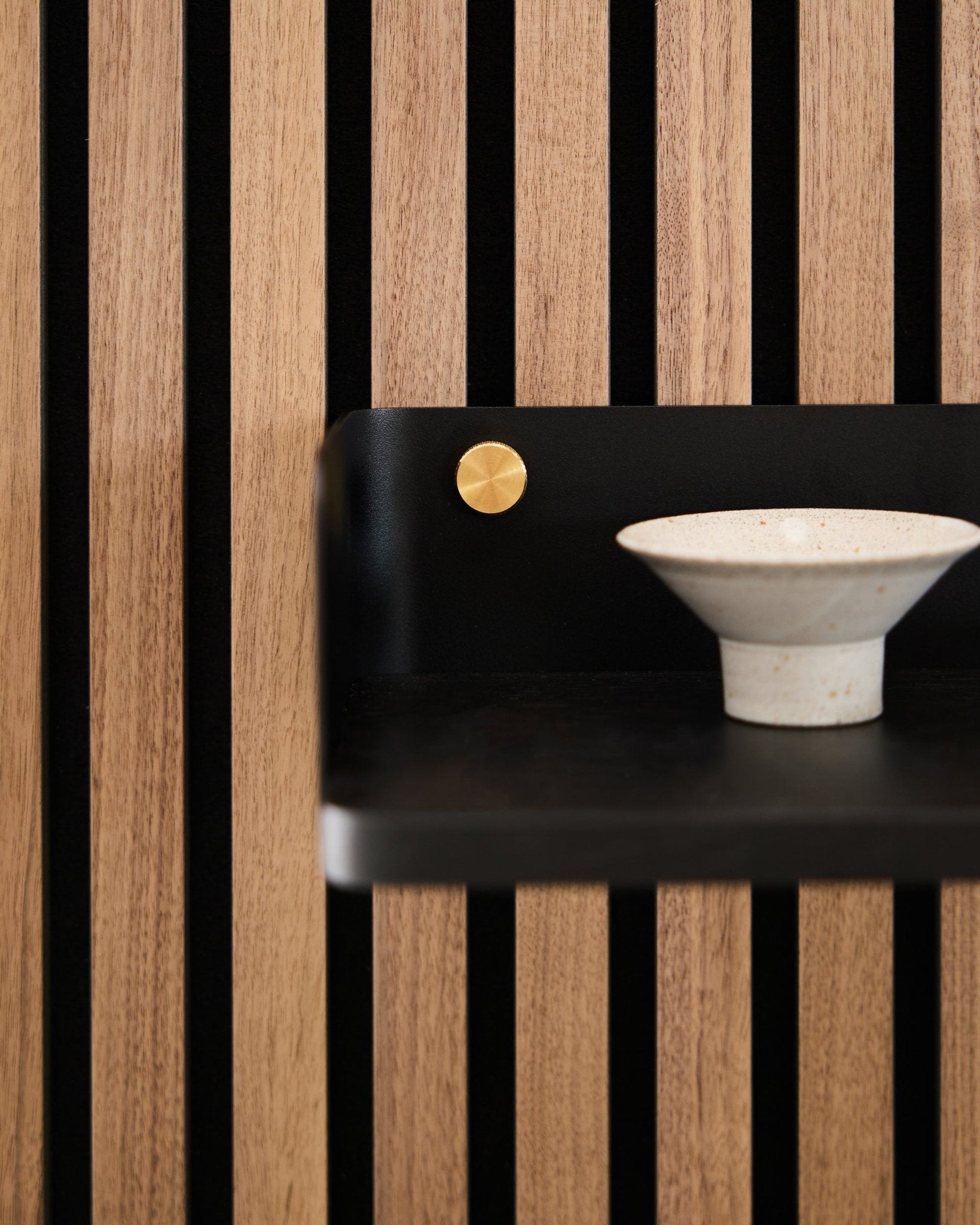 Keramisk skål plassert på Linn Bokhylle fra WoodUpp, 39,9 cm i black oak med vertical black spiler og en brass aksent, som gjenspeiler nordisk minimalistisk design.