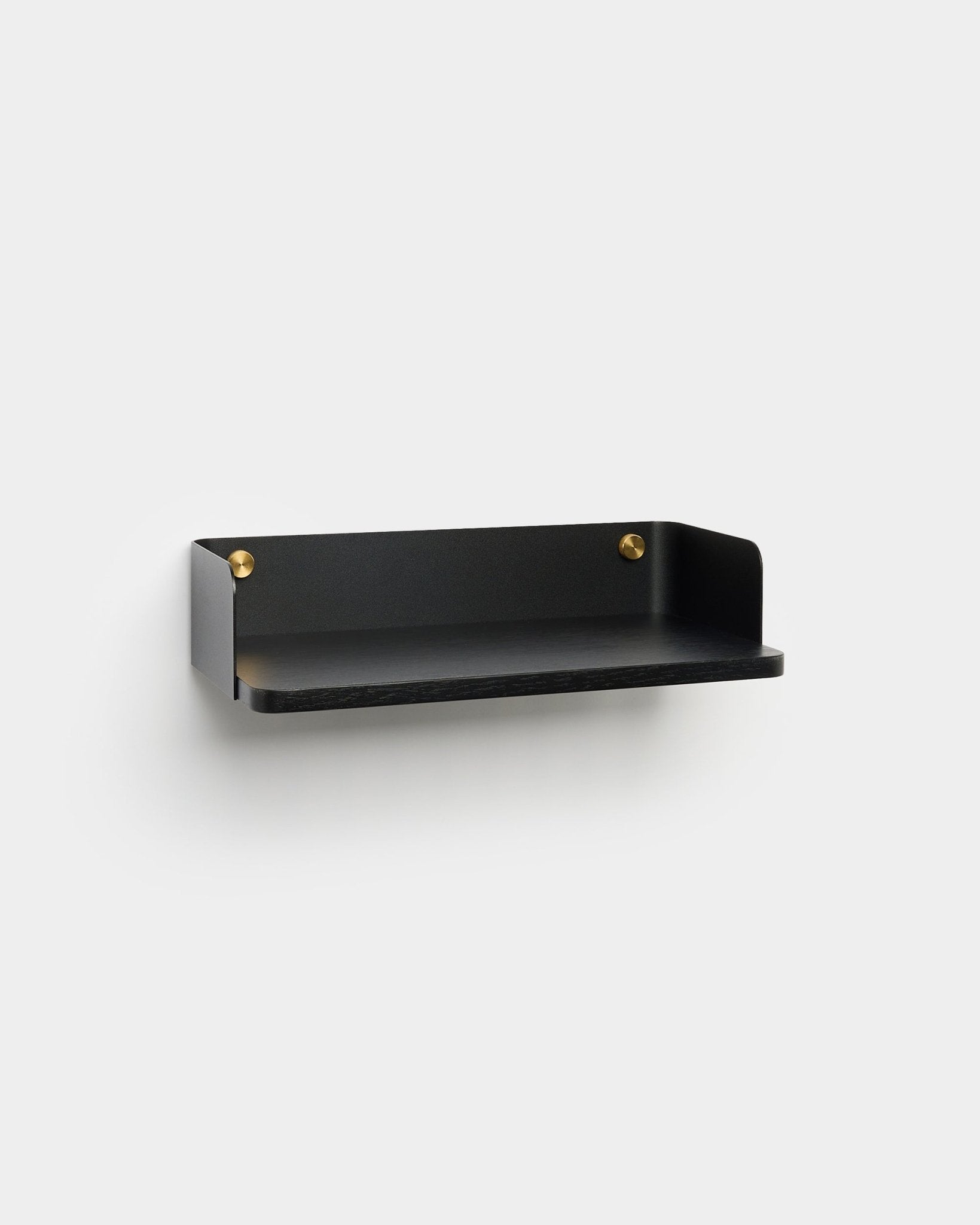 Linn Bokhylle fra WoodUpp, i en minimalistisk black finish med brass monteringsskruer, er montert på en lys grå vegg og kompletterer nordisk interiørdesign.