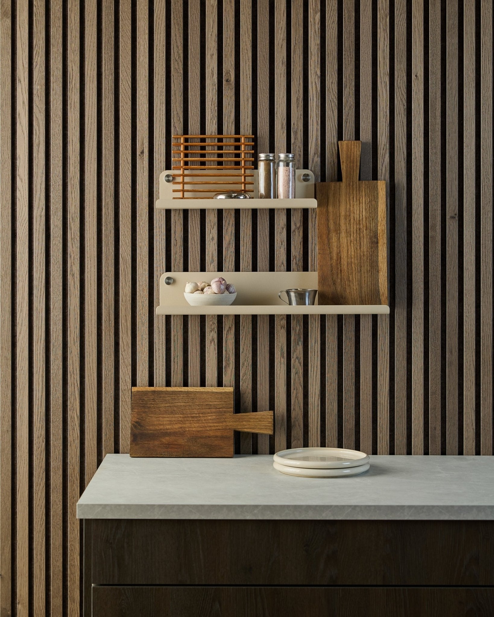Minimalistisk kjøkken med nordisk Akupanel akustisk spilevegg i tre, åpne hyller med krydder og skåler, benkeplate med hvite tallerkener og et skjærebrett.