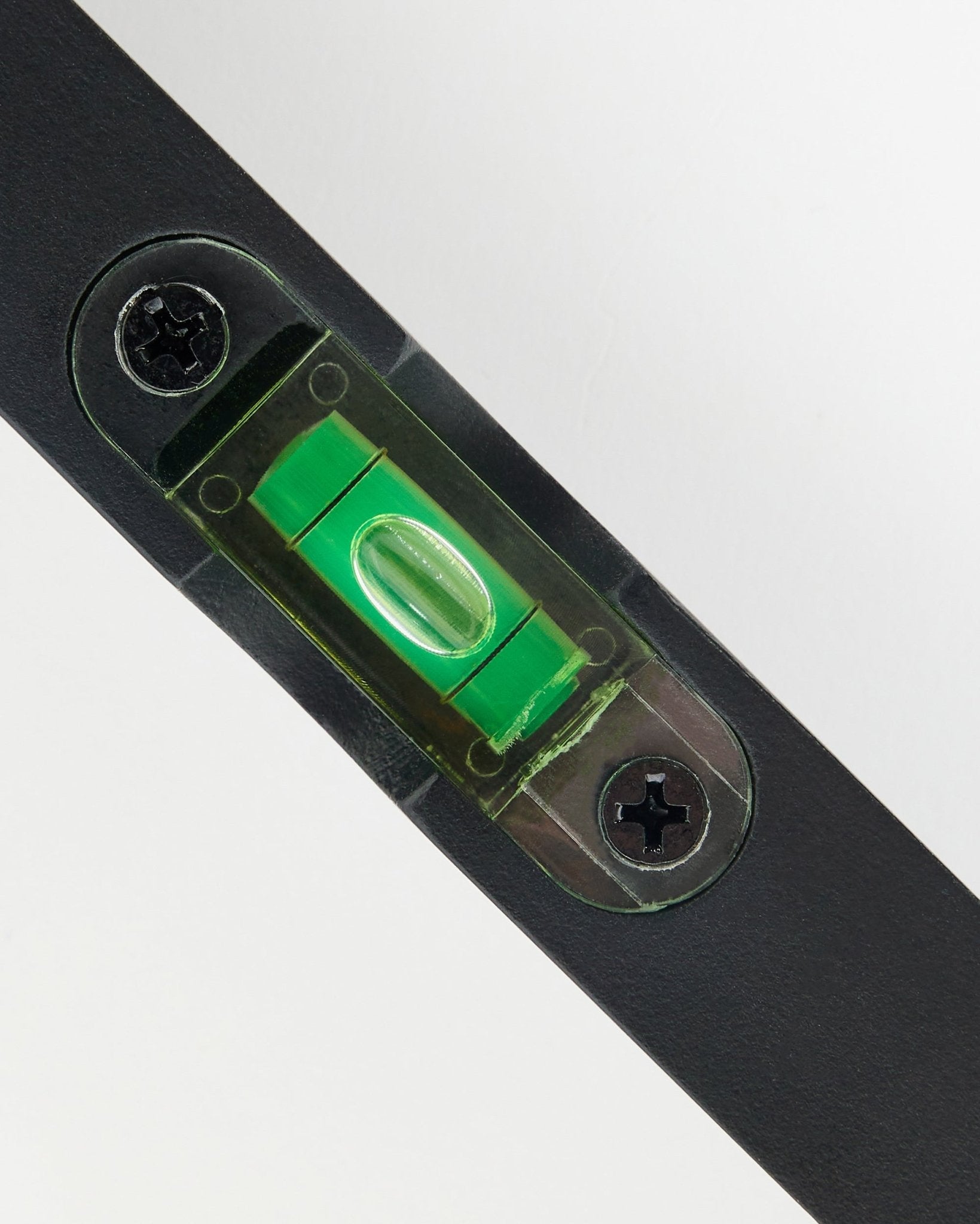 Nærbilde av et black WoodUpp vater (15 x 3.2 cm) med grønt libelleglass, brukt til presis Montering av akustikkpaneler.