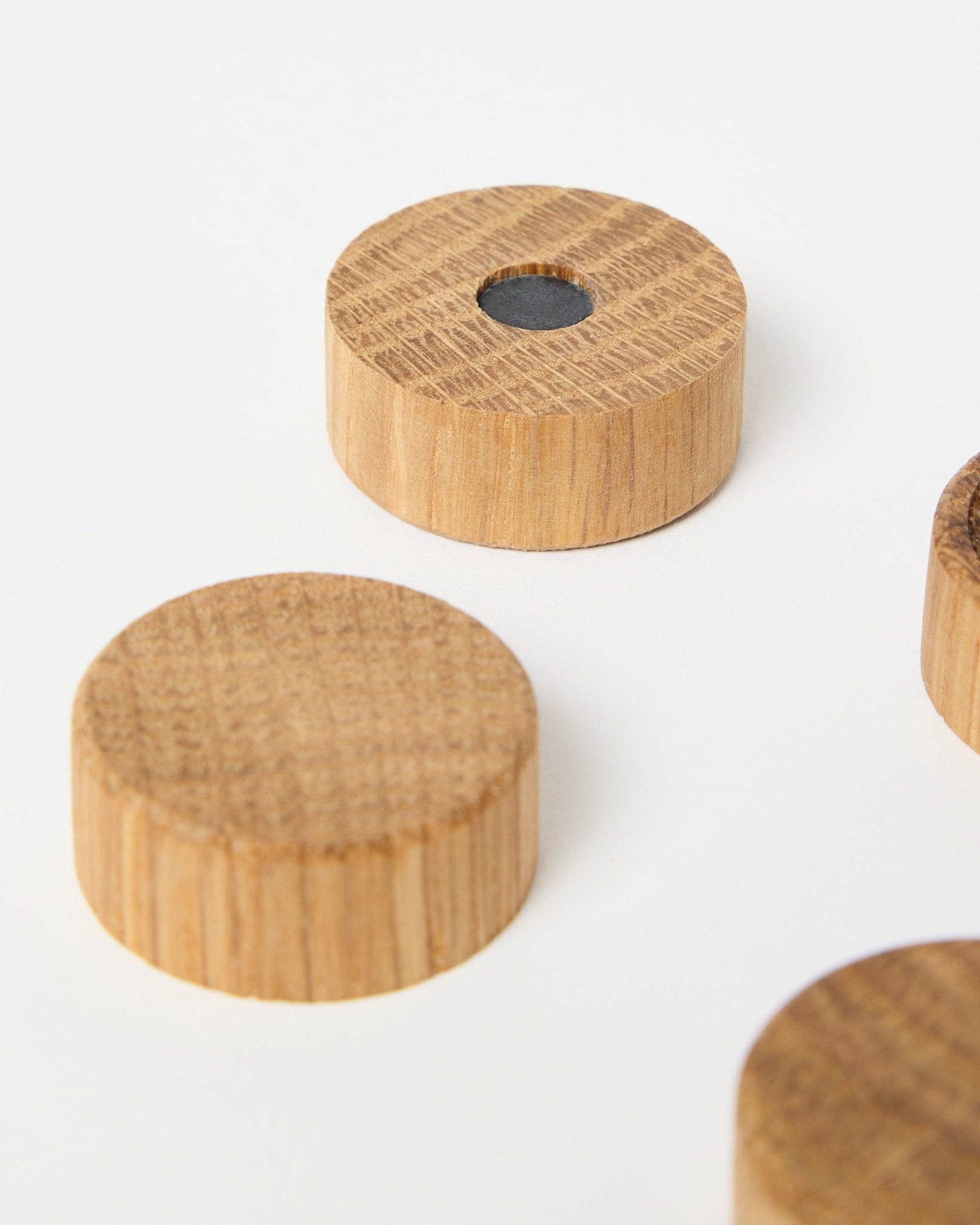 Sett med fire natural oak magneter fra WoodUpp, laget for bruk med Akupanel akustiske trepaneler, hvor én har en sentral neodymmagnet for ekstra feste, vist på hvit bakgrunn.