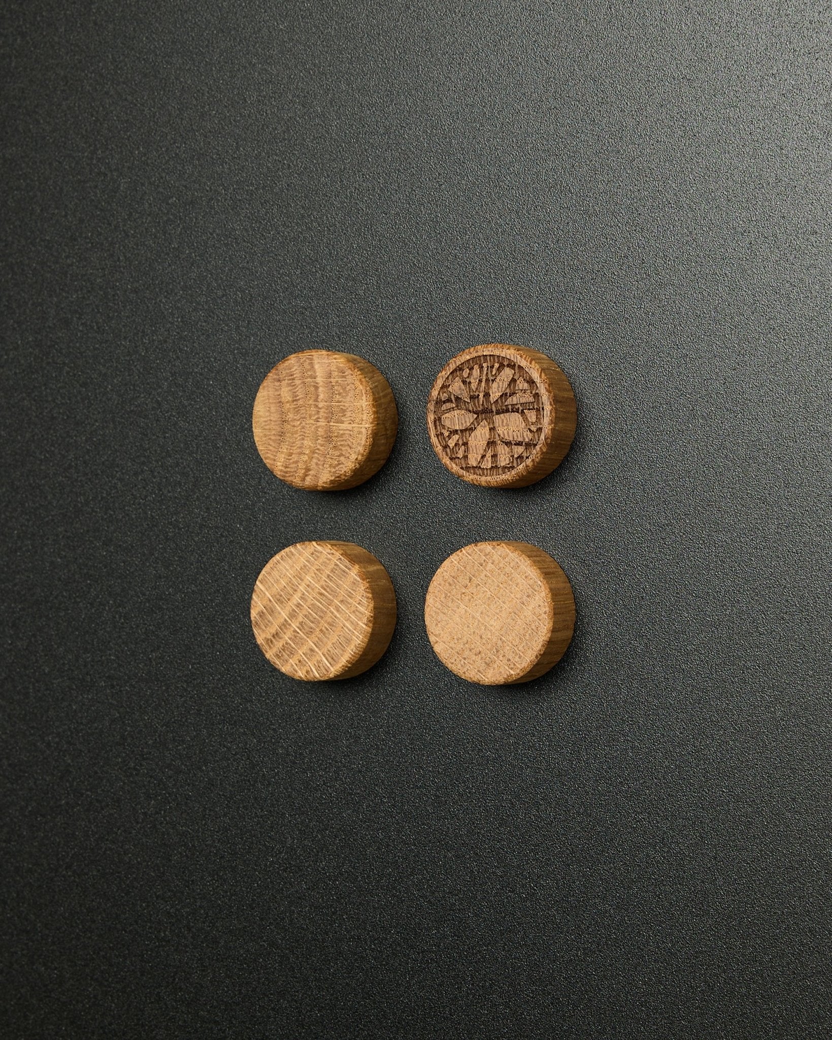 Sett med fire massive natural oak magneter fra WoodUpp, hvor én har et utskåret sitrusskive-design, laget for bruk med Norr Magnetic Board Akustikkpanel.