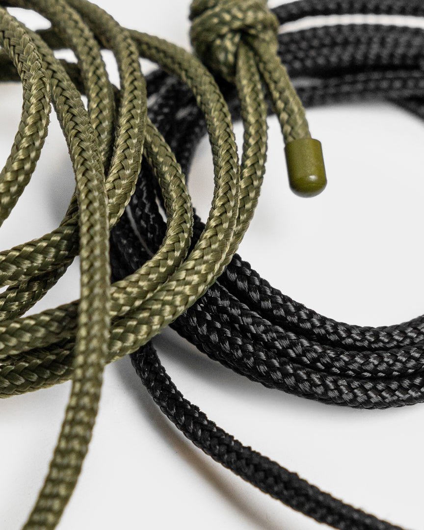 Vindar | Gallery String fra WoodUpp: flettet grønn og black snor med plasttupper, vist ved siden av en fotosnor mot en hvit bakgrunn.