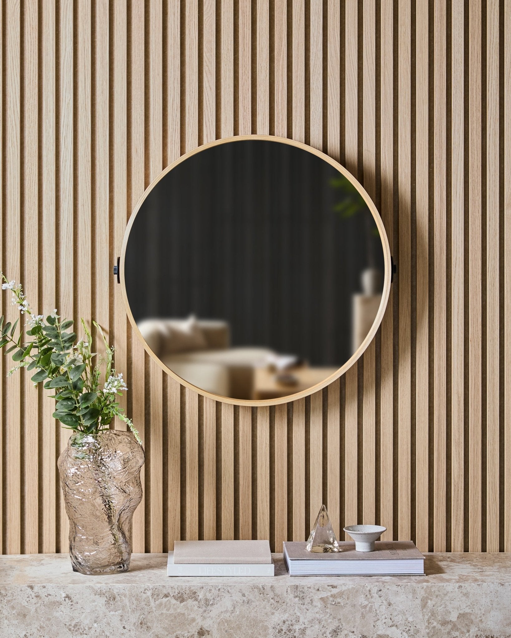 Linn | Mirror i Natural Oak fra WoodUpp er montert på en nordisk spilevegg Akustikkpanel over en steinhylle med en glassvase, bøker og dekorobjekter.