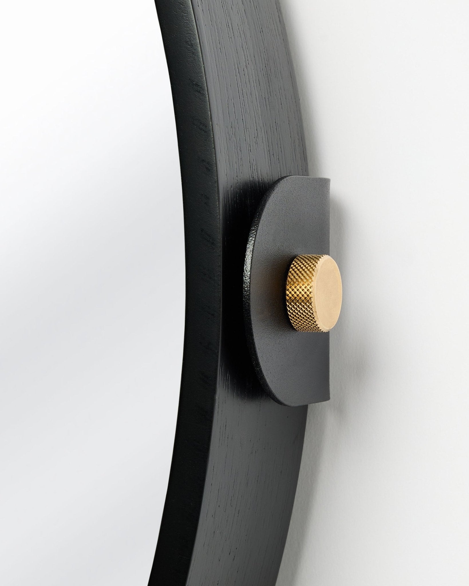Detalj av Linn | Mirror / Black Oak Akustikkpanel fra WoodUpp, montert på veggen med en gullfarget knott og justerbar vinkel.