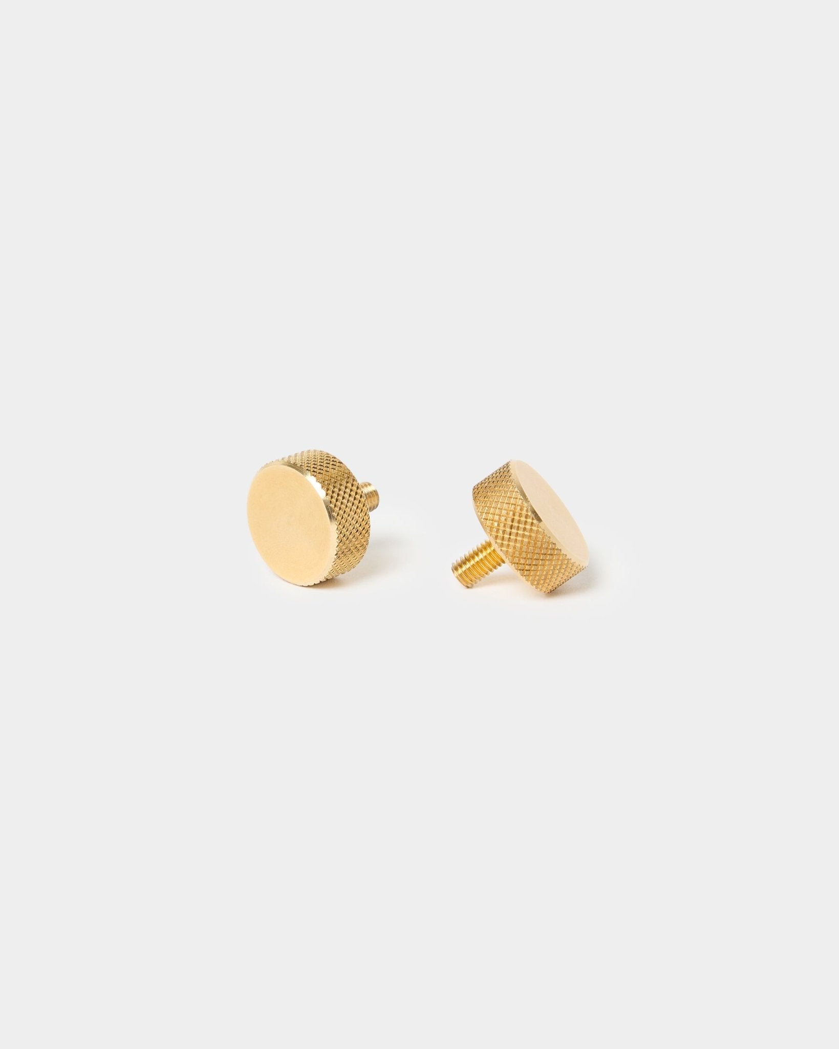 Par med WoodUpp brass fingerskruer (M5x10 mm, 20x8,8), med teksturerte kanter og korte stammer, laget for Akupanel tilbehør, på en enkel lys bakgrunn.