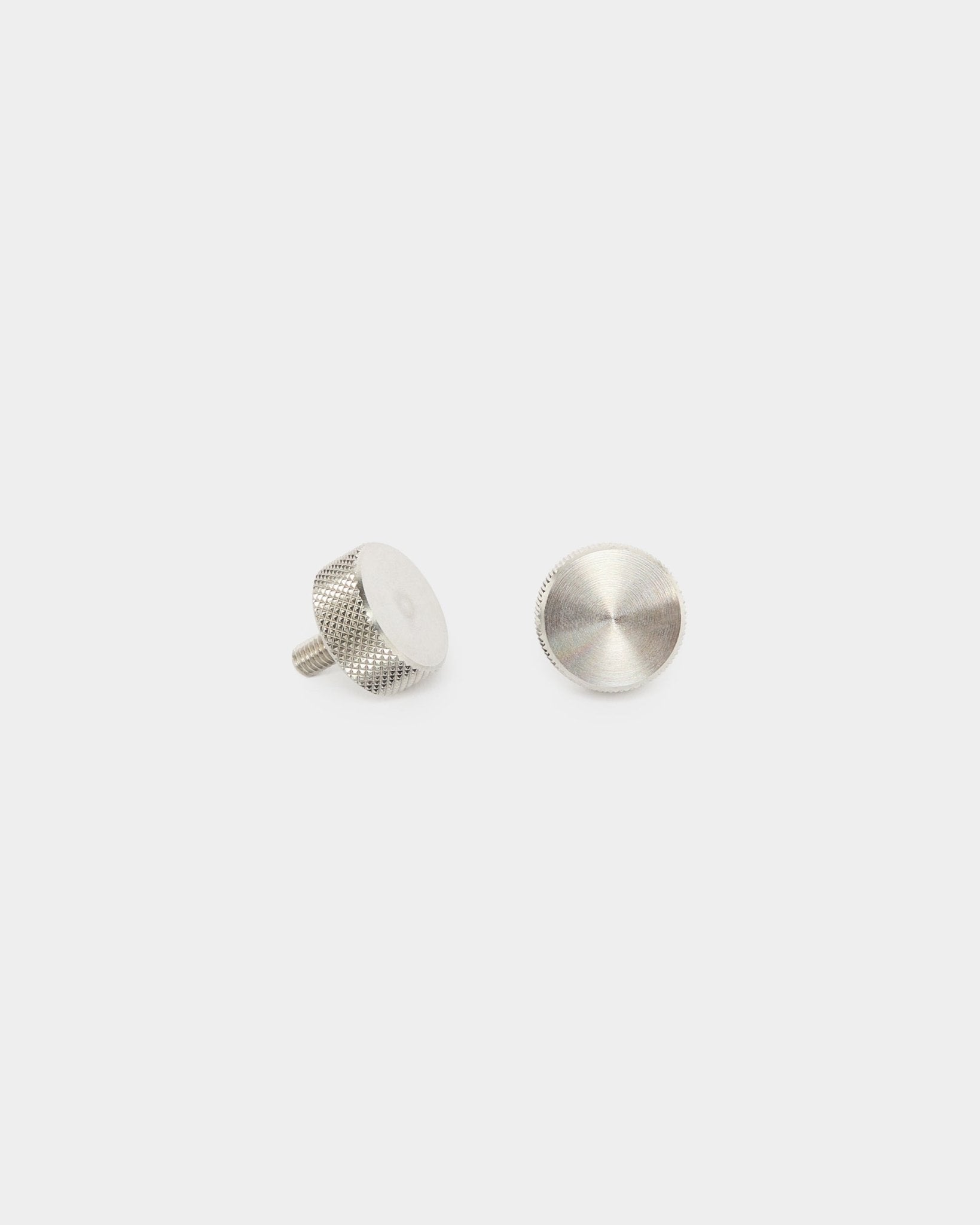 To WoodUpp finger-skruer i rustfritt steel (M5x10 mm, 20x8.8), tilbehør til Akupanel akustikkpaneler, vist stående og liggende flatt på en ren hvit bakgrunn.