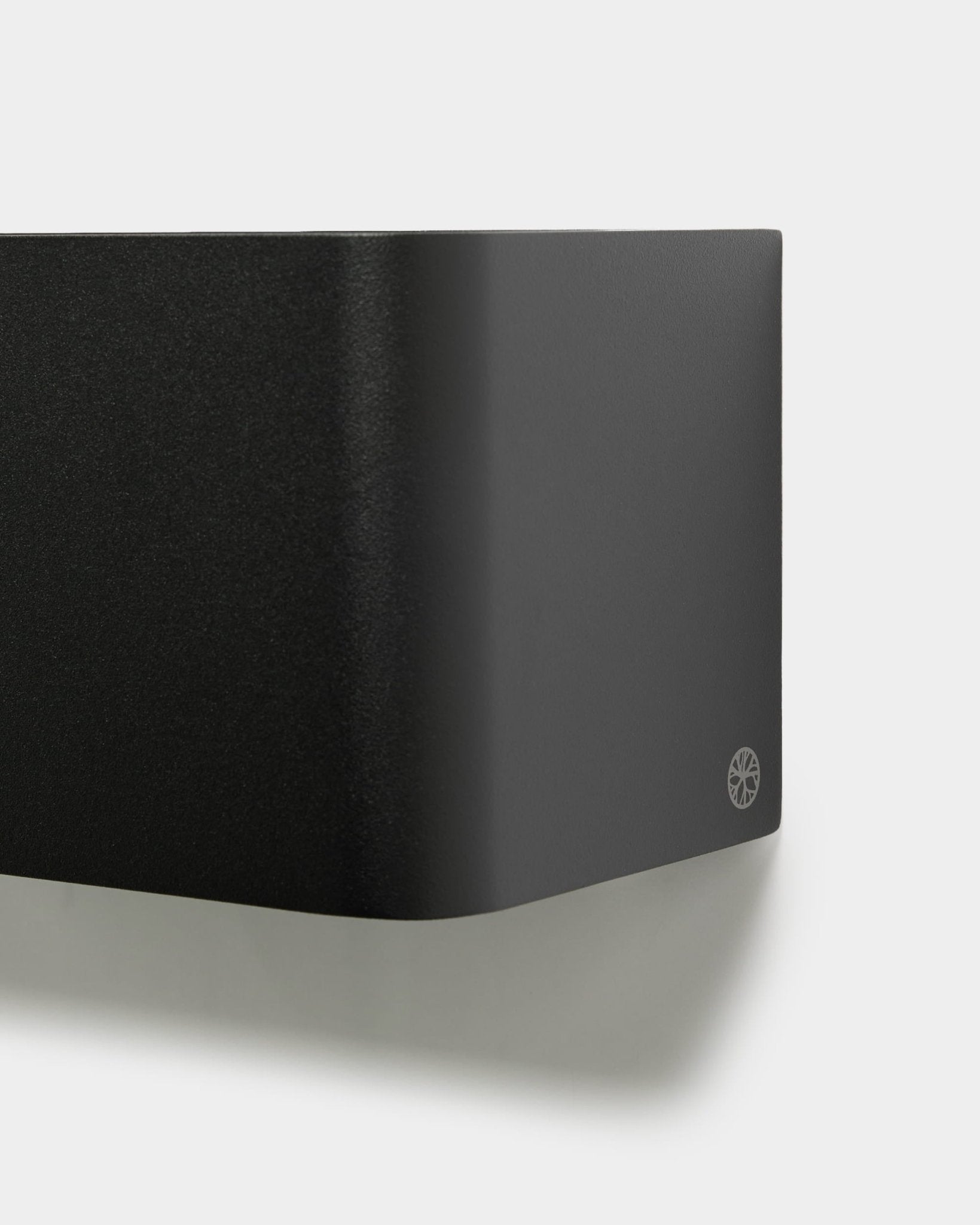 Nærbilde av den minimalistiske WoodUpp Norr Plant Box (23,9 cm, black) med avrundede kanter og logo, montert på en hvit vegg. Nordisk design av akustisk tilbehør.