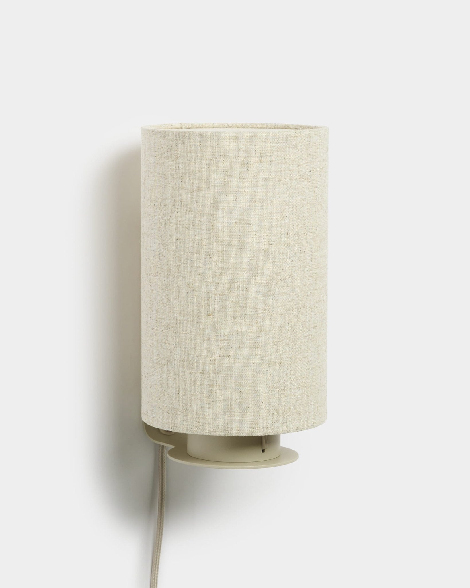 Feya | Wall Lamp fra WoodUpp med en sylinderformet skjerm i lin-bomull og synlig hvit ledning, beige finish, designet for å passe sammen med akustiske trepaneler.