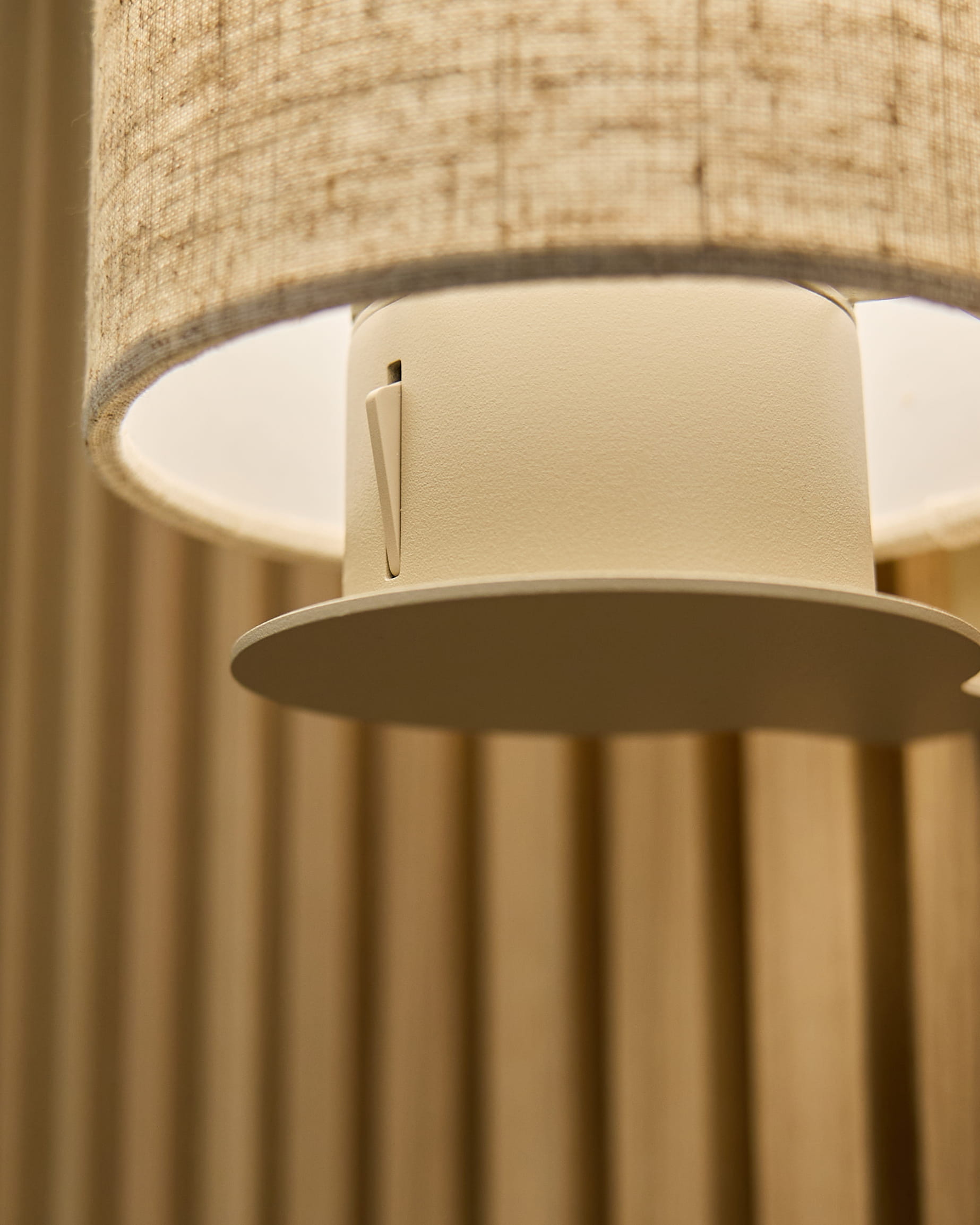 Nærbilde av Feya vegglampe i Beige/Beige fra WoodUpp, med en skjerm i lin-bomull og sylinderformet armatur montert på vertical beige akustiske paneler.
