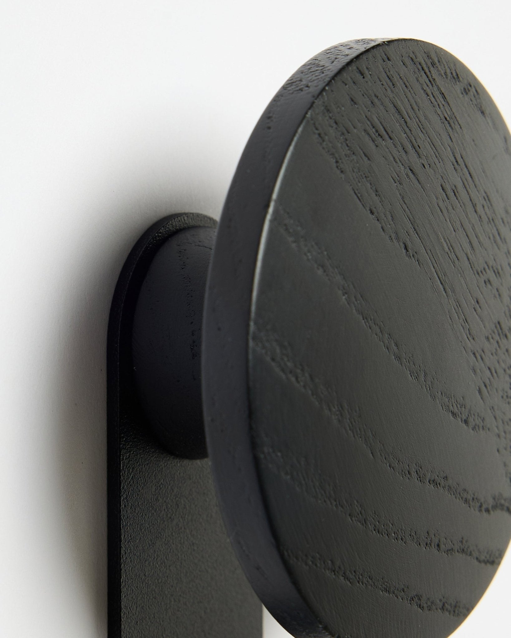 Nærbilde av WoodUpp Linn | Vertical Hanger i Black Oak, som fremhever den detaljerte trestrukturen mot en hvit Akupanel Akustikkpanel bakgrunn.