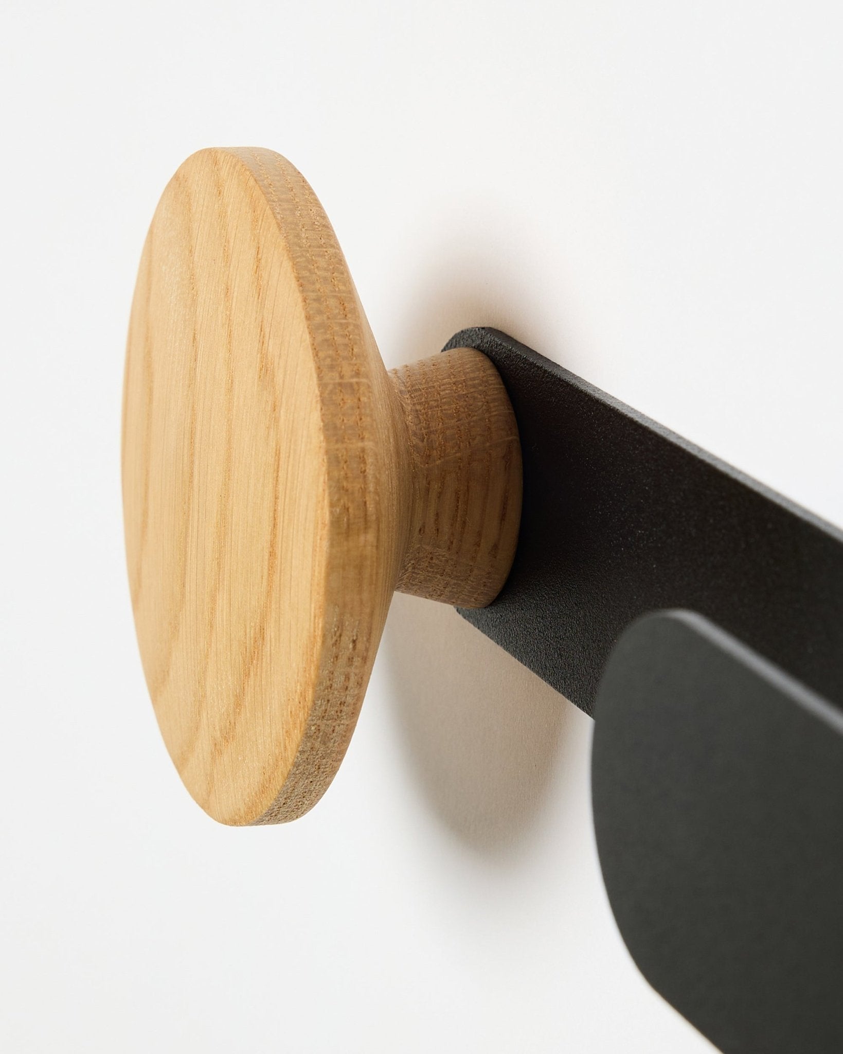 Nærbilde av WoodUpp Linn Horizontal Hanger i natural oak på en black metallbrakett, utformet for Akupanel akustikkpaneler eller som en funksjonell veggkrok.