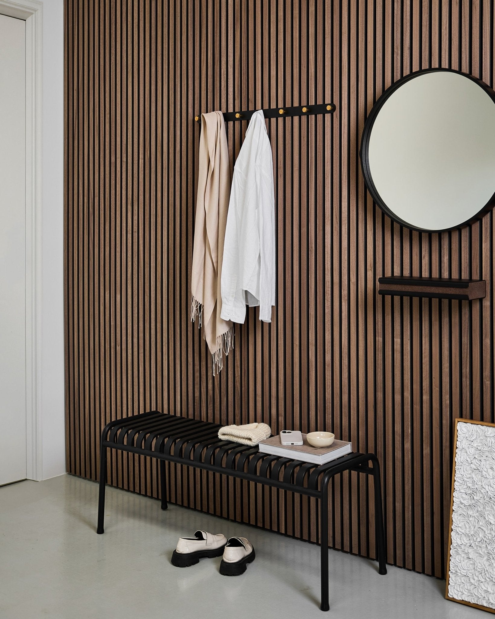 Minimalistisk entré med en WoodUpp Akupanel akustisk spilevegg, Norr Coat Hook Rack (Black/Brass, X7), benk, speil og moderne dekor i nøytrale toner.