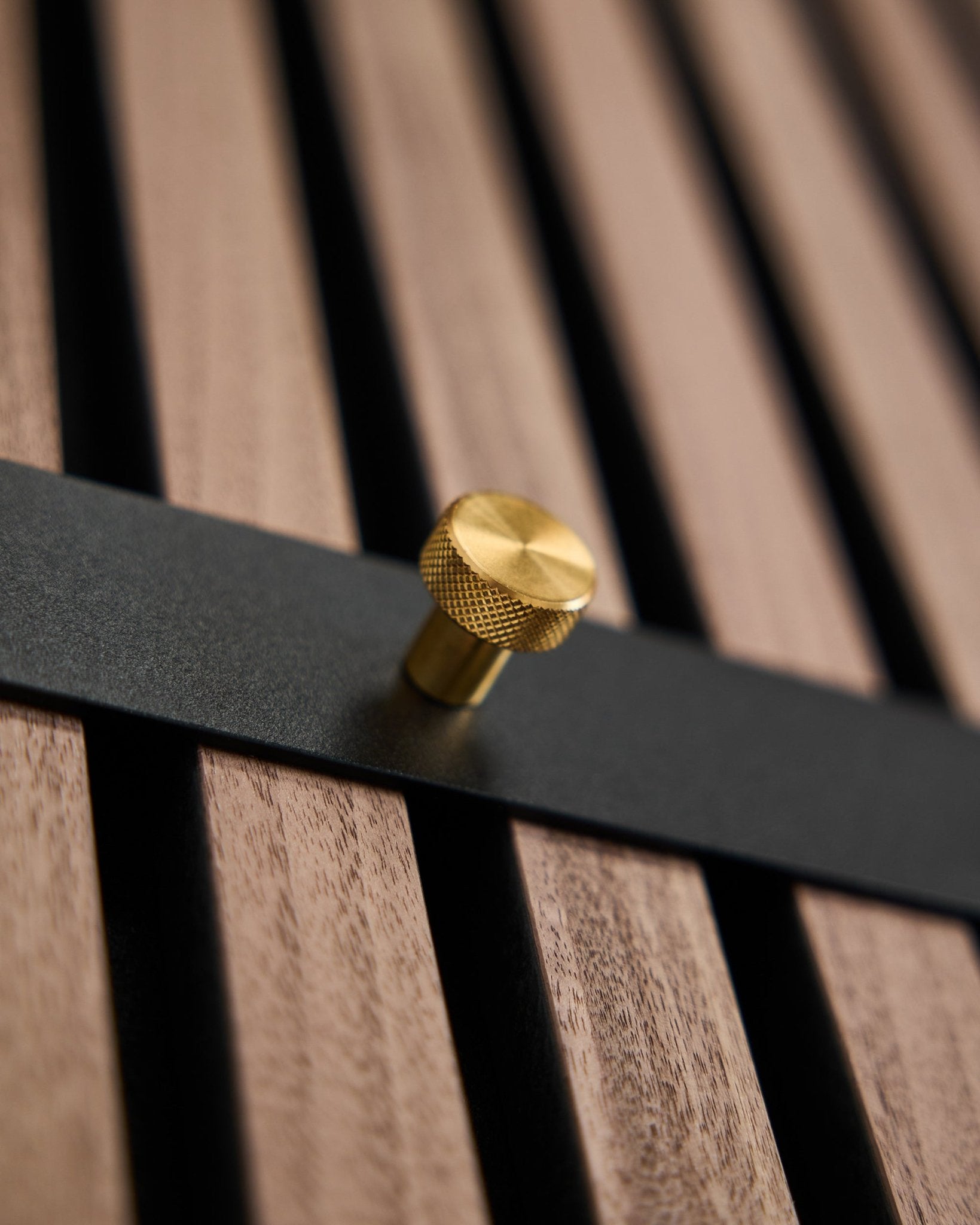 WoodUpp Norr Coat Hook Rack har syv black kroker med brass knotter montert på et brown spilepanel, utformet som et nordisk tilbehør for Akupanel.