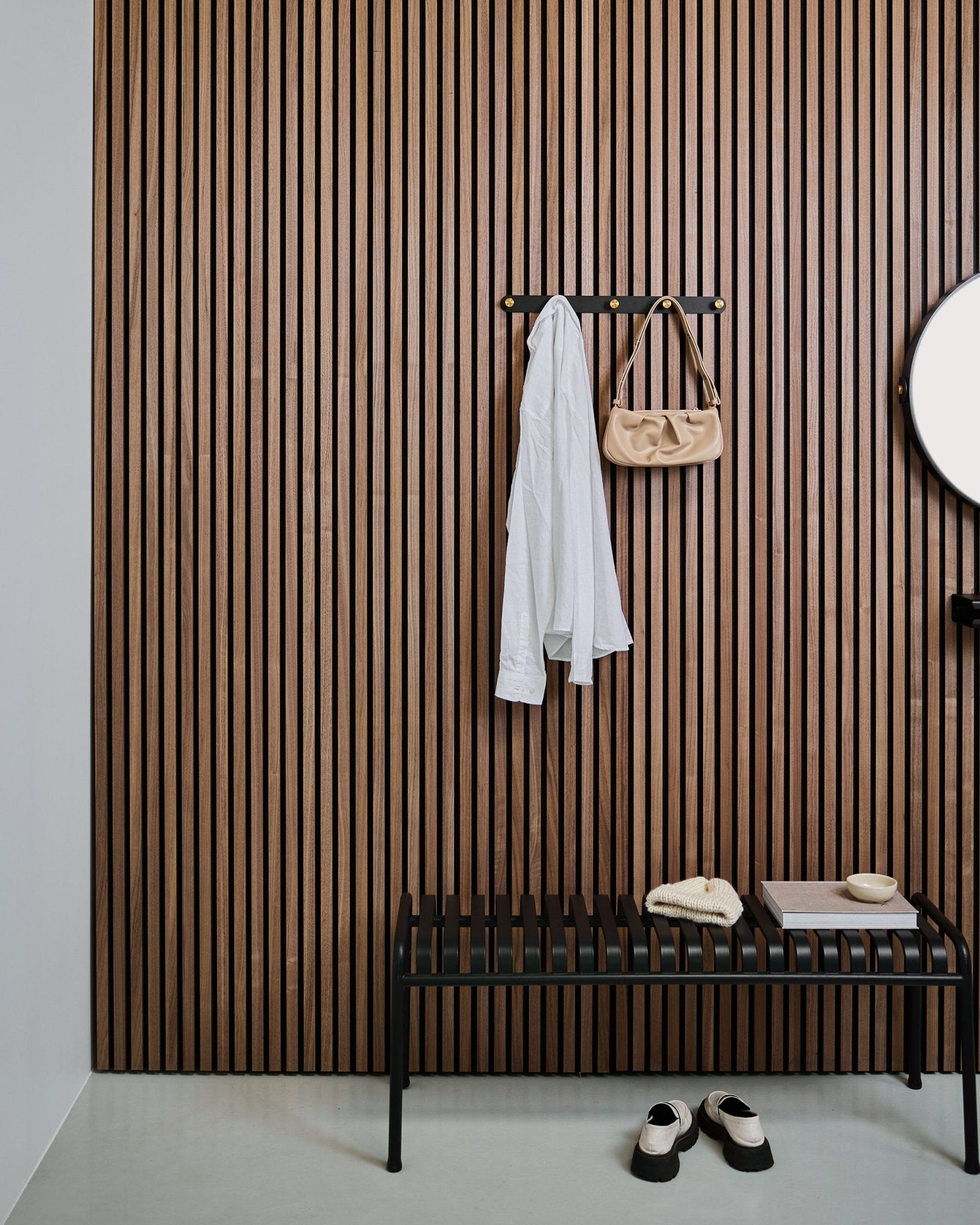 WoodUpp Norr knaggrekke i black og brass holder en hvit skjorte og beige veske over en black benk; hvite tøfler er pent plassert under.