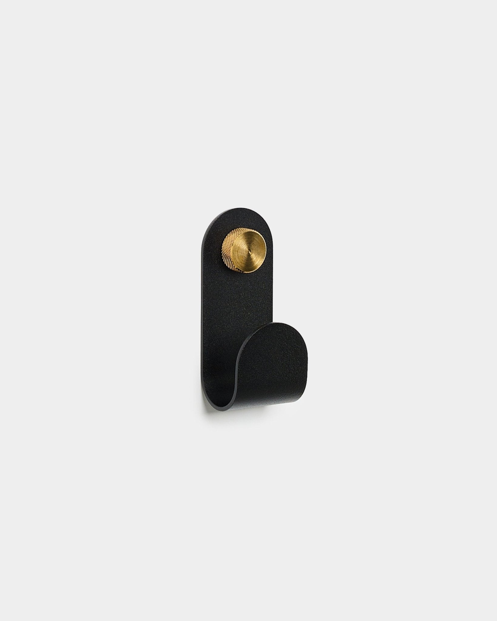 Norr Single Hanger i black fra WoodUpp, med buet design og en rund brass-detalj, vist mot en enkel hvit bakgrunn.