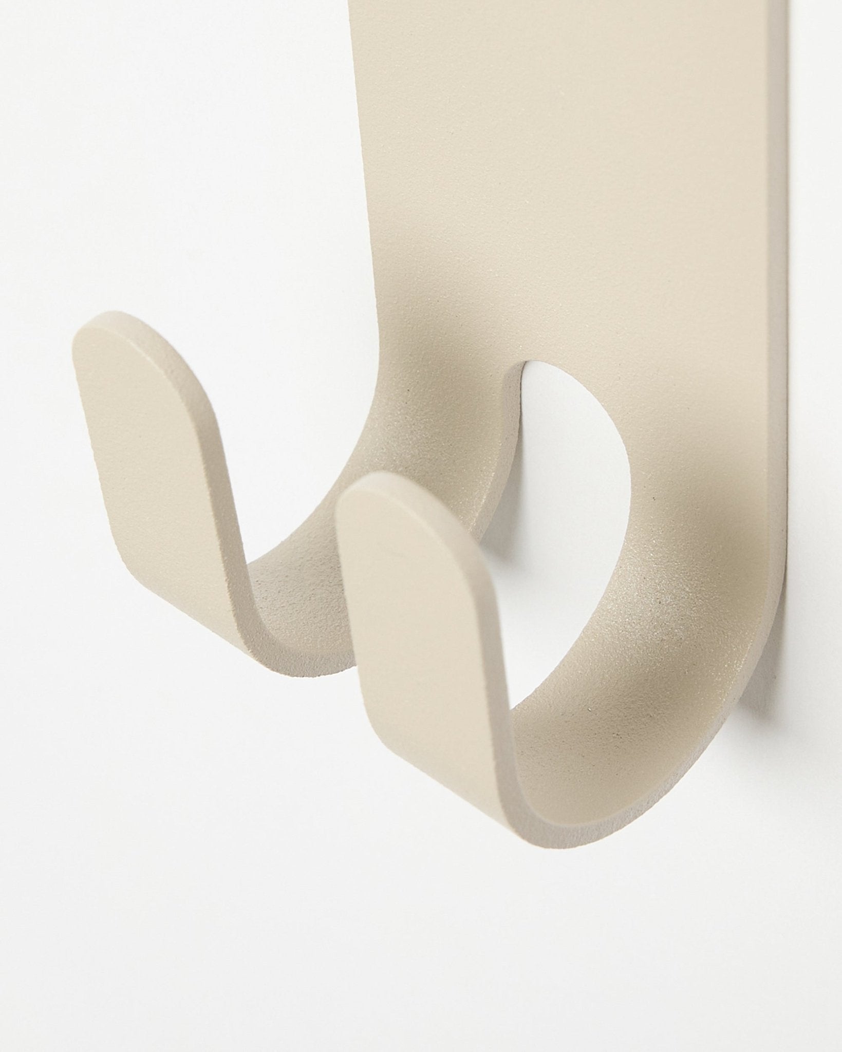 Nærbilde av Norr Double Hanger i beige fra WoodUpp, en minimalistisk knagg i metall montert på et lyst colored Akustikkpanel.