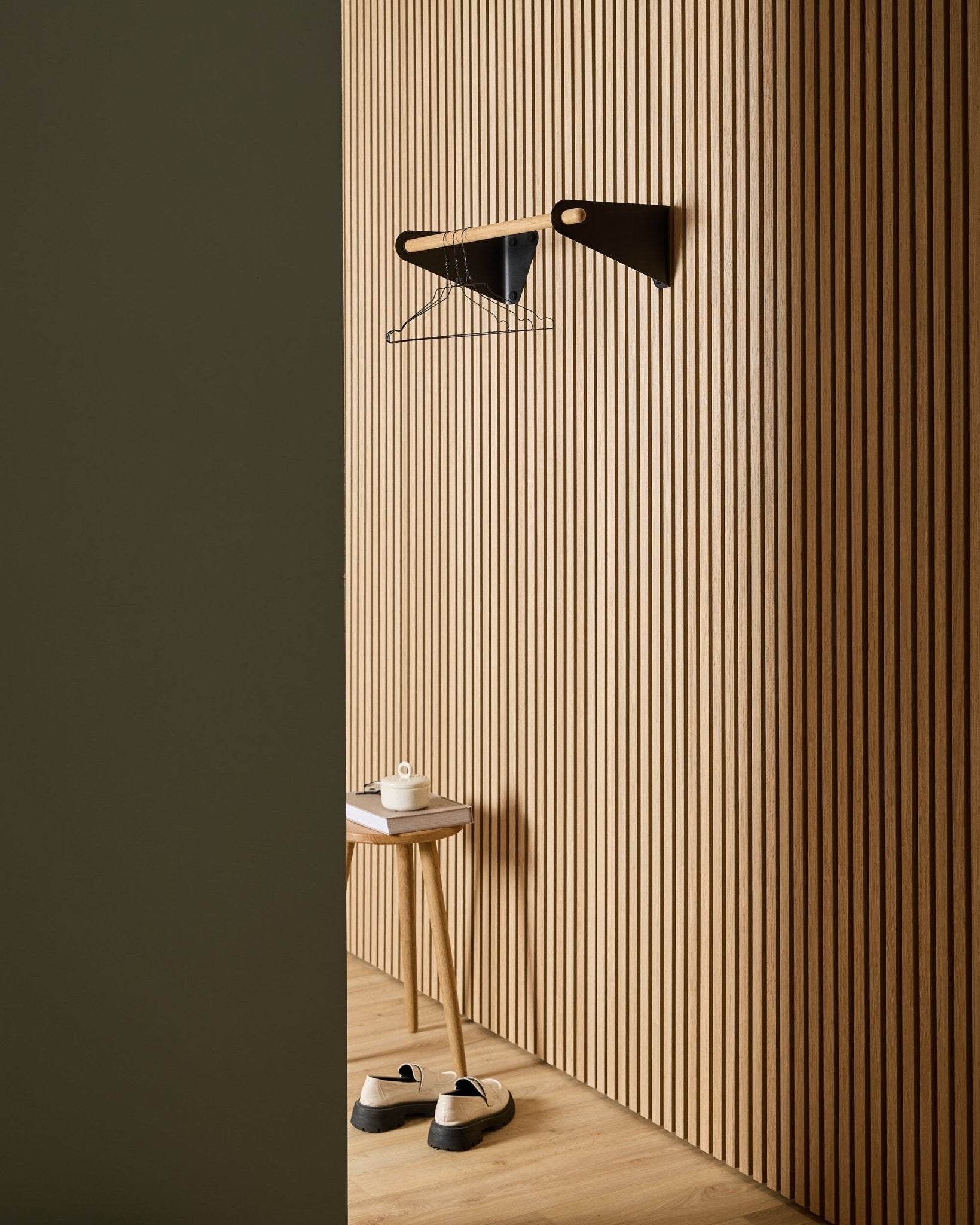 Minimalistisk entré med WoodUpp Akupanel Nordic akustiske trespilepaneler, black Linn Coat Rail (75,9 cm), krakk, sko, vegghylle og papirrull.