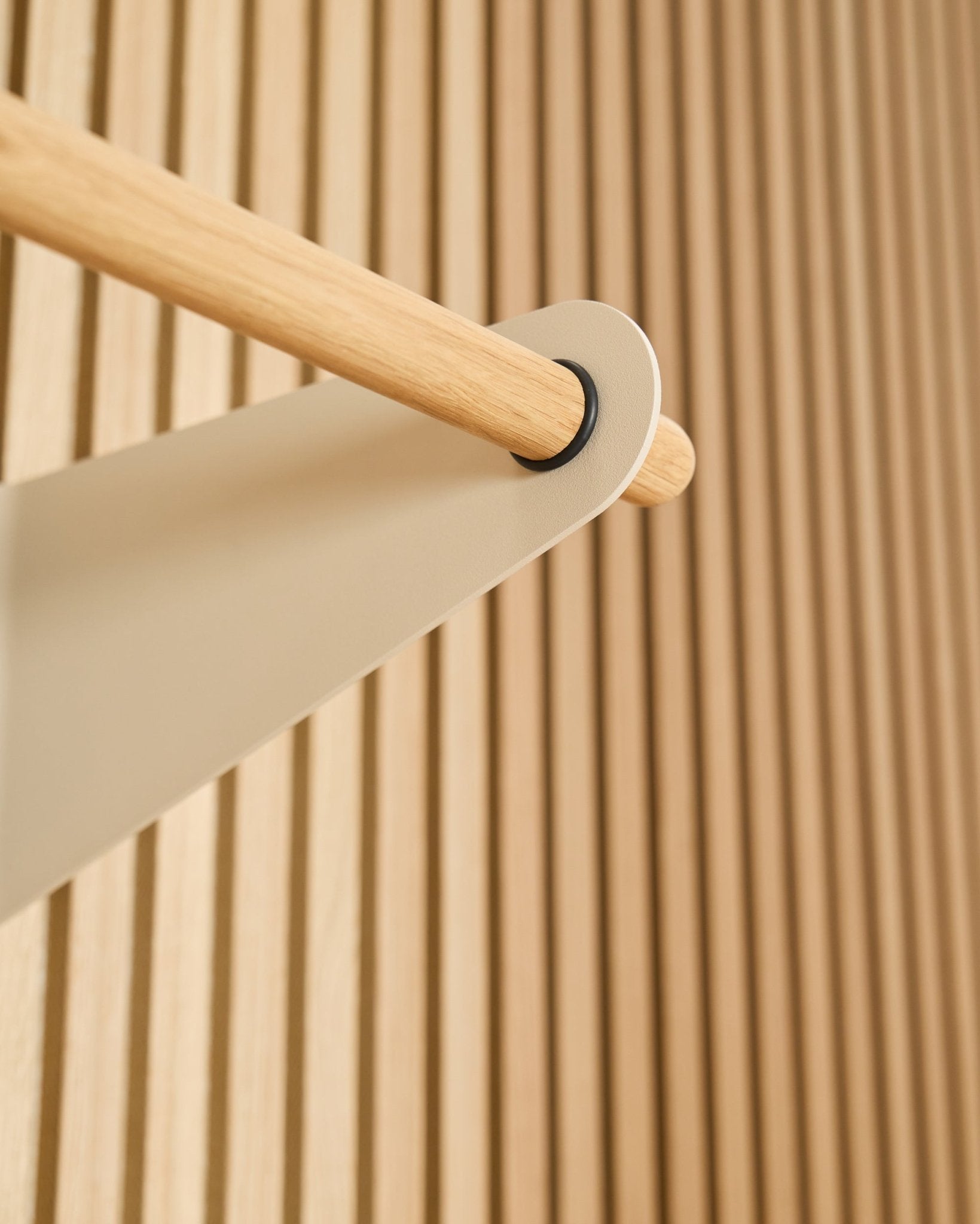 Nærbilde av WoodUpp Linn knaggrekke i beige (75,9 cm), montert på en beige metallbrakett mot et teksturert Akupanel akustisk spilepanel.