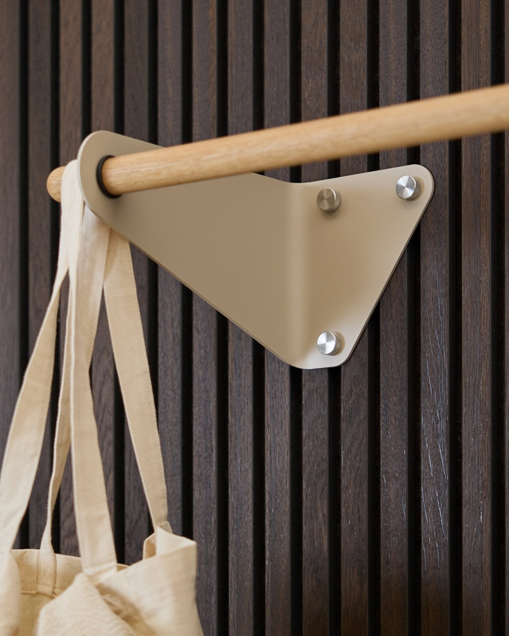 Beige WoodUpp Linn klesstang (115,9 cm) montert på Akupanel Akustikkpanel, med en kremfarget stoffveske på venstre side.