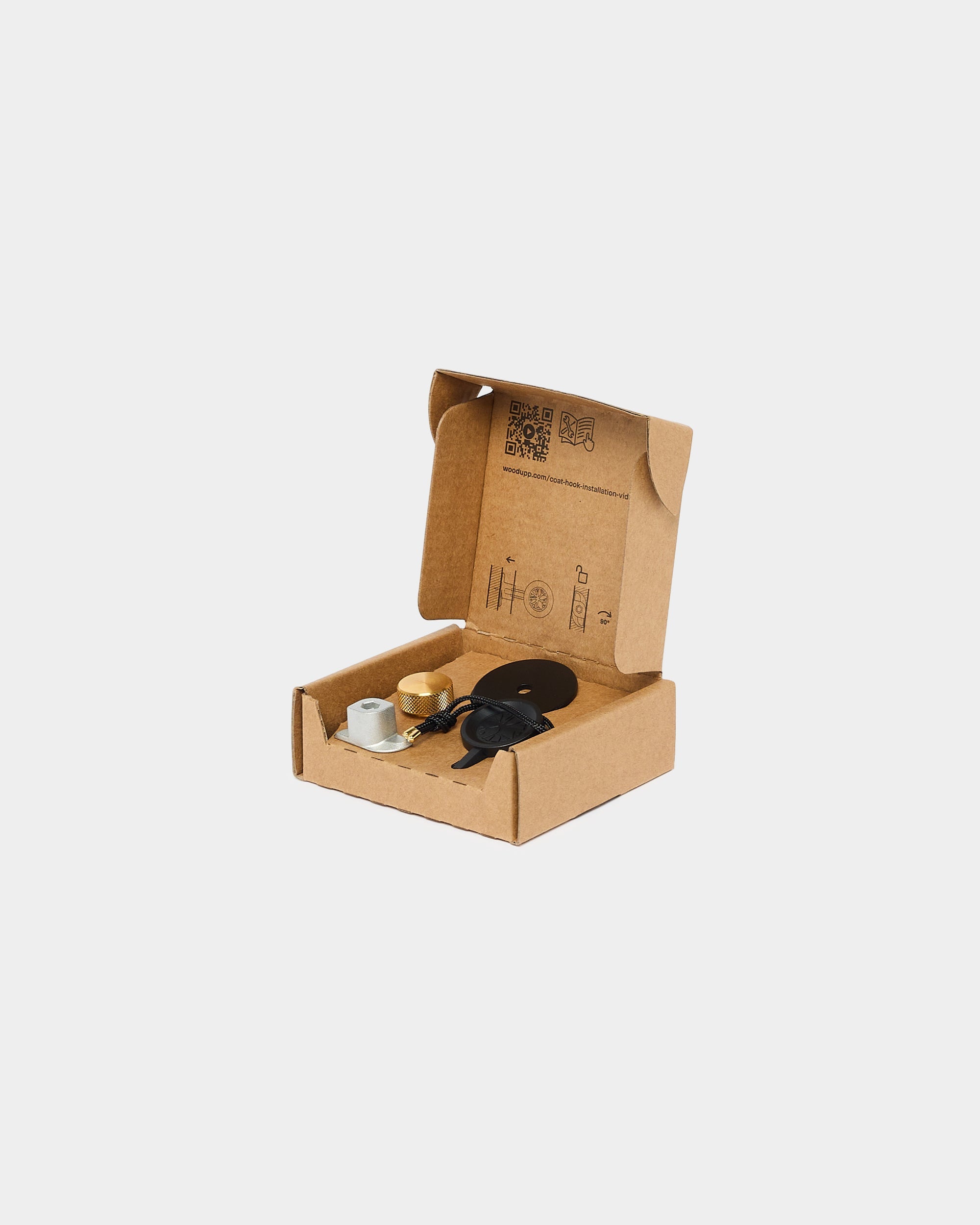 Open cardboard box containing assembly tools, components, USB cable, circular part, tape, and other accessories for acoustic wood panel installation on plain background.