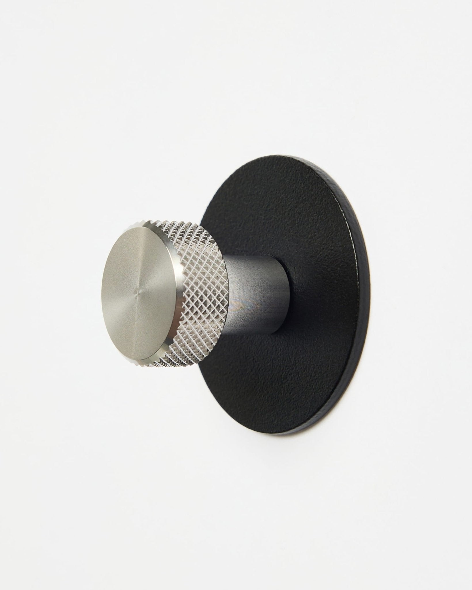 WoodUpp Norr | Coat Hook X1 i black og rustfritt steel montert på en enkel hvit vegg, utformet som et tilbehør i CREATE-kolleksjonen for Akupanel systemer.