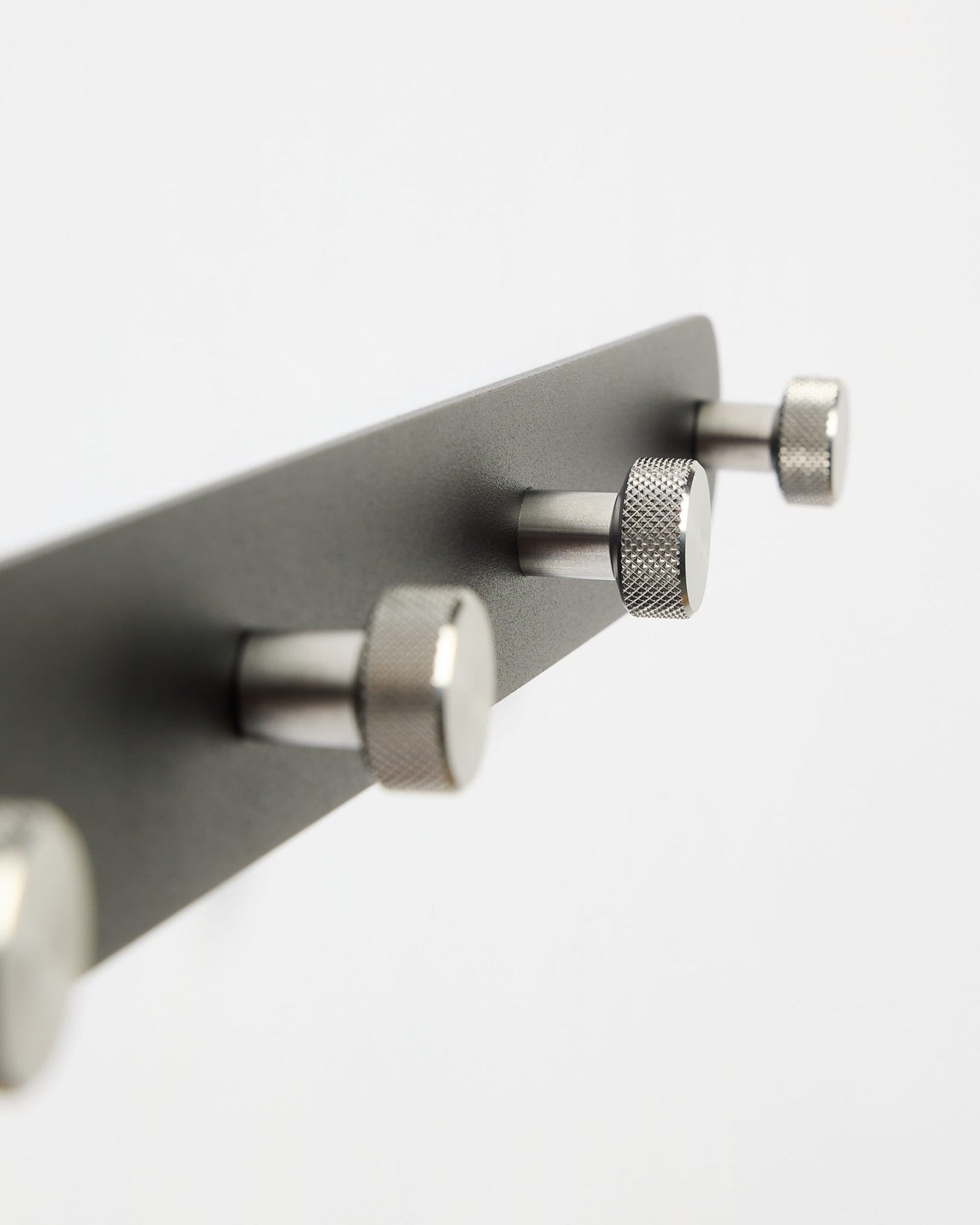 WoodUpp Norr Coat Hook Rack X7 i svart og rustfritt stål med sju kroker, vist mot en ren hvit bakgrunn; del av CREATE-tilbehørskolleksjonen.