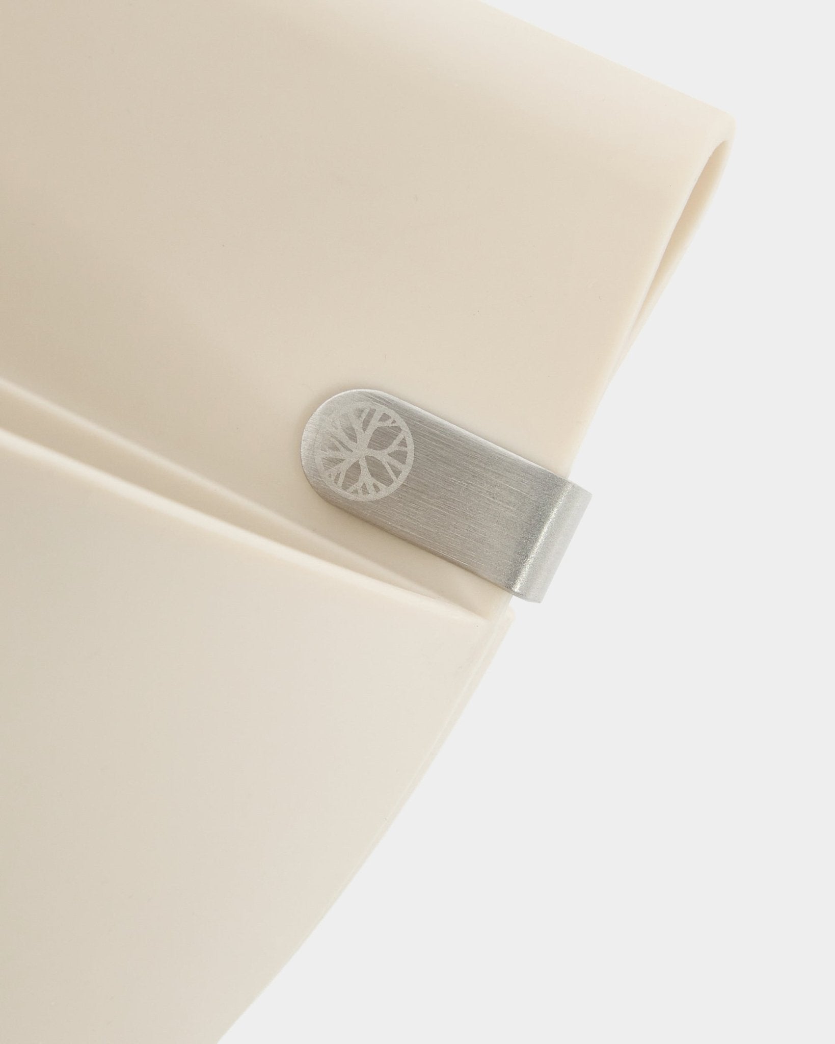 Nærbilde av et WoodUpp Gro | Soft Pocket / BM2-panel (4 l) i lys beige med metallklips og inngravert sirkeldetalj mot en ren hvit bakgrunn.