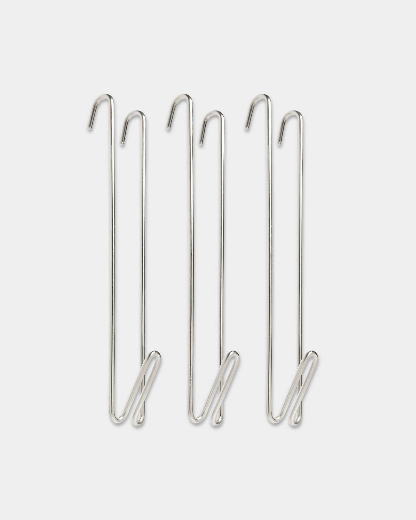Tre WoodUpp Alva wire hook garderobestangforlengere i rustfritt steel og BM1, laget for å gi ekstra opphengsplass ved siden av akustiske trepaneler.