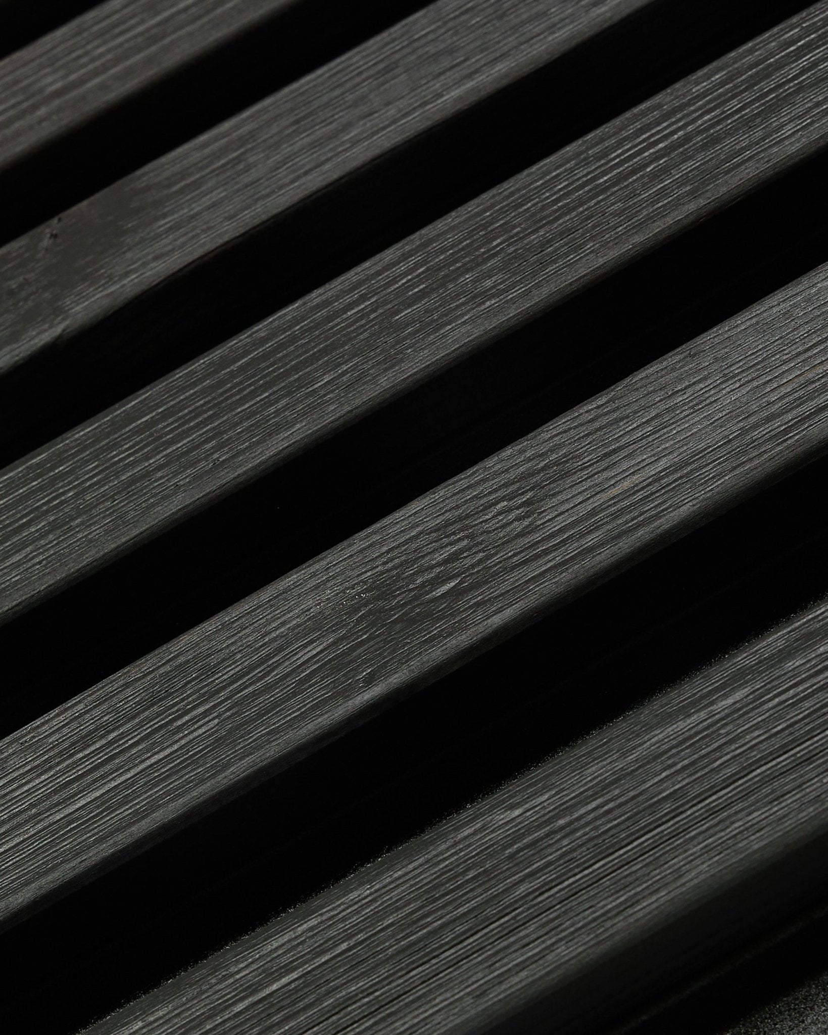 Aluwood utendørs fasadepanel fra WoodUpp, Thermowood i black utførelse, 240 x 45.1 cm, med diagonale spiler i nordisk gran med synlig åretegning og skygge.