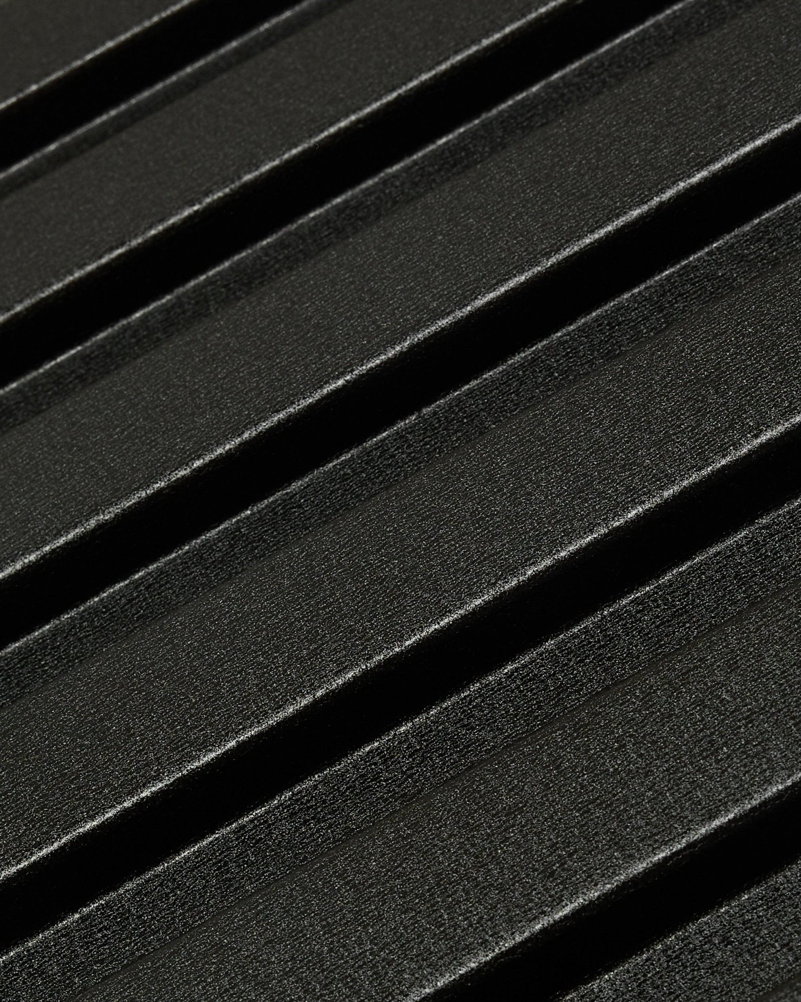 Nærbilde av Aluwood utendørs fasadepanel fra WoodUpp: mørk, teksturert overflate i resirkulert aluminium med diagonale opphøyde riller, størrelse 240 x 45,1 cm.