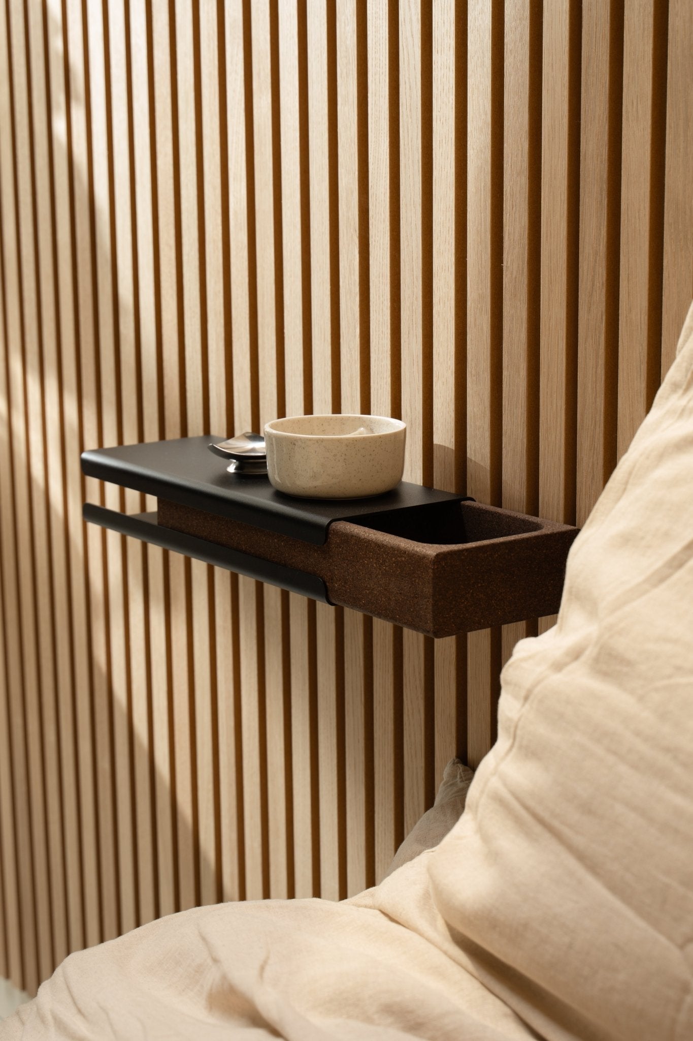 Minimalistisk vegghylle med en keramisk skål og WoodUpp Norr Key Tray ved siden av en beige pute og Akupanel Akustikkpanel, opplyst av mykt naturlig lys.