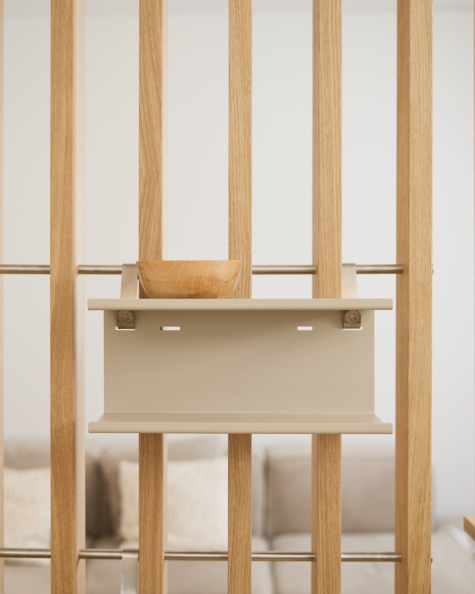 En small treskål på beige Nell Double Metal Shelf fra WoodUpp (31,7 cm), med en uskarp sofa og puter i bakgrunnen.