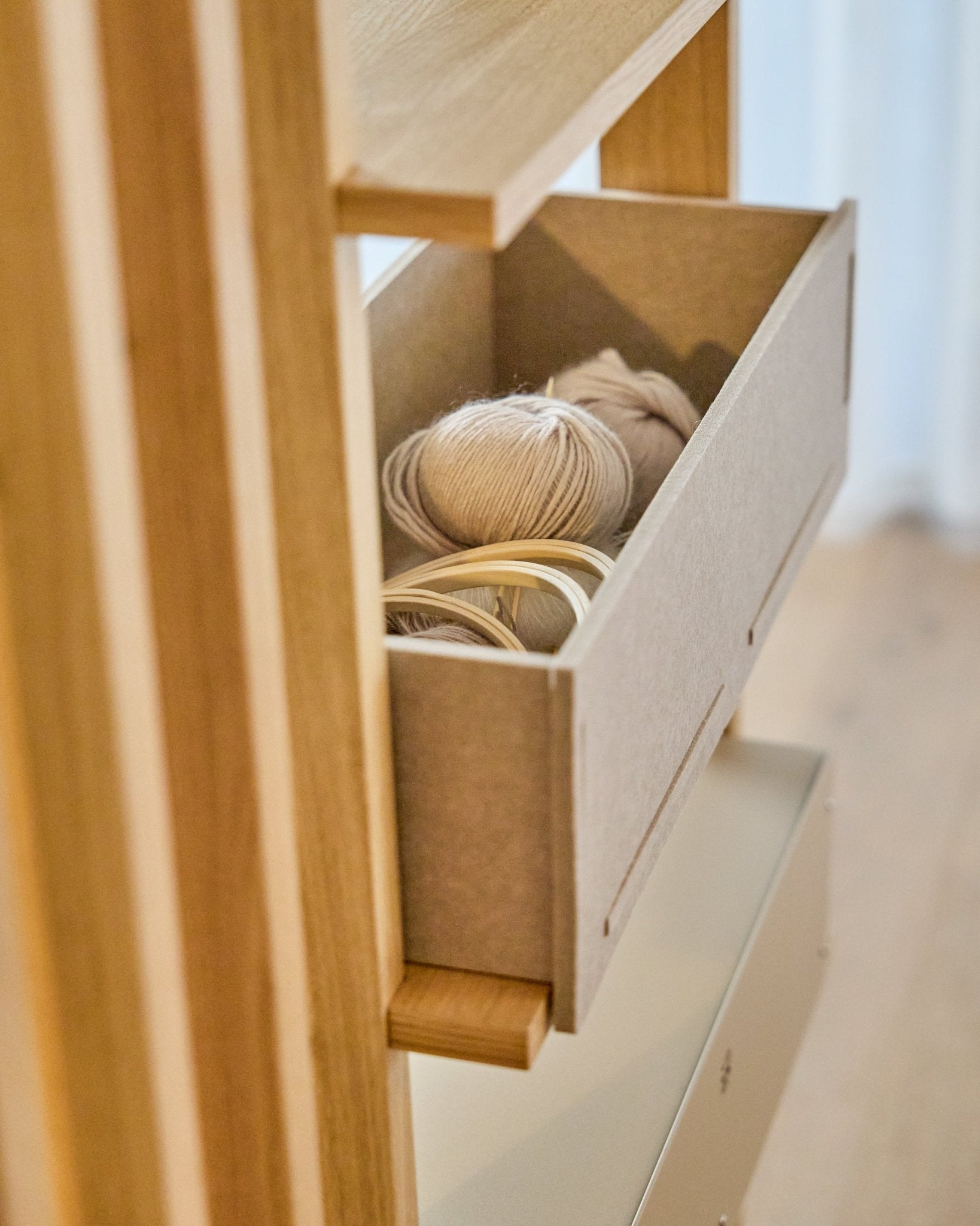 WoodUpp Vigg Felt Box / BM2 i beige rommer lette garnnøster og broderiringer i tre på en trehylle, og passer fint sammen med nordiske akustiske paneler.