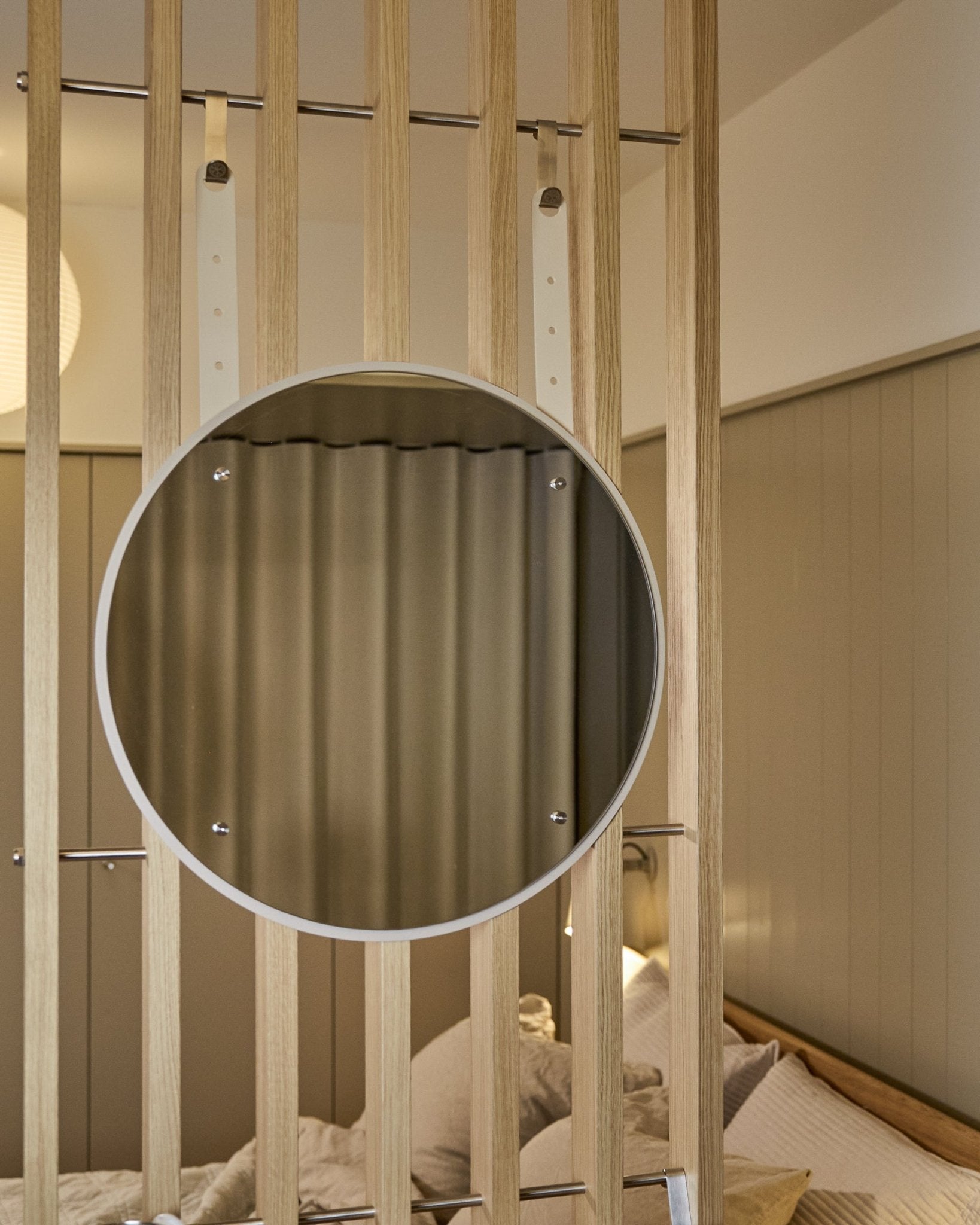 Rundt, høydejusterbart Vala BM1-speil fra WoodUpp, 54 cm i diameter, montert på vertical akustisk spilepanel i tre med myk, nøytral belysning.