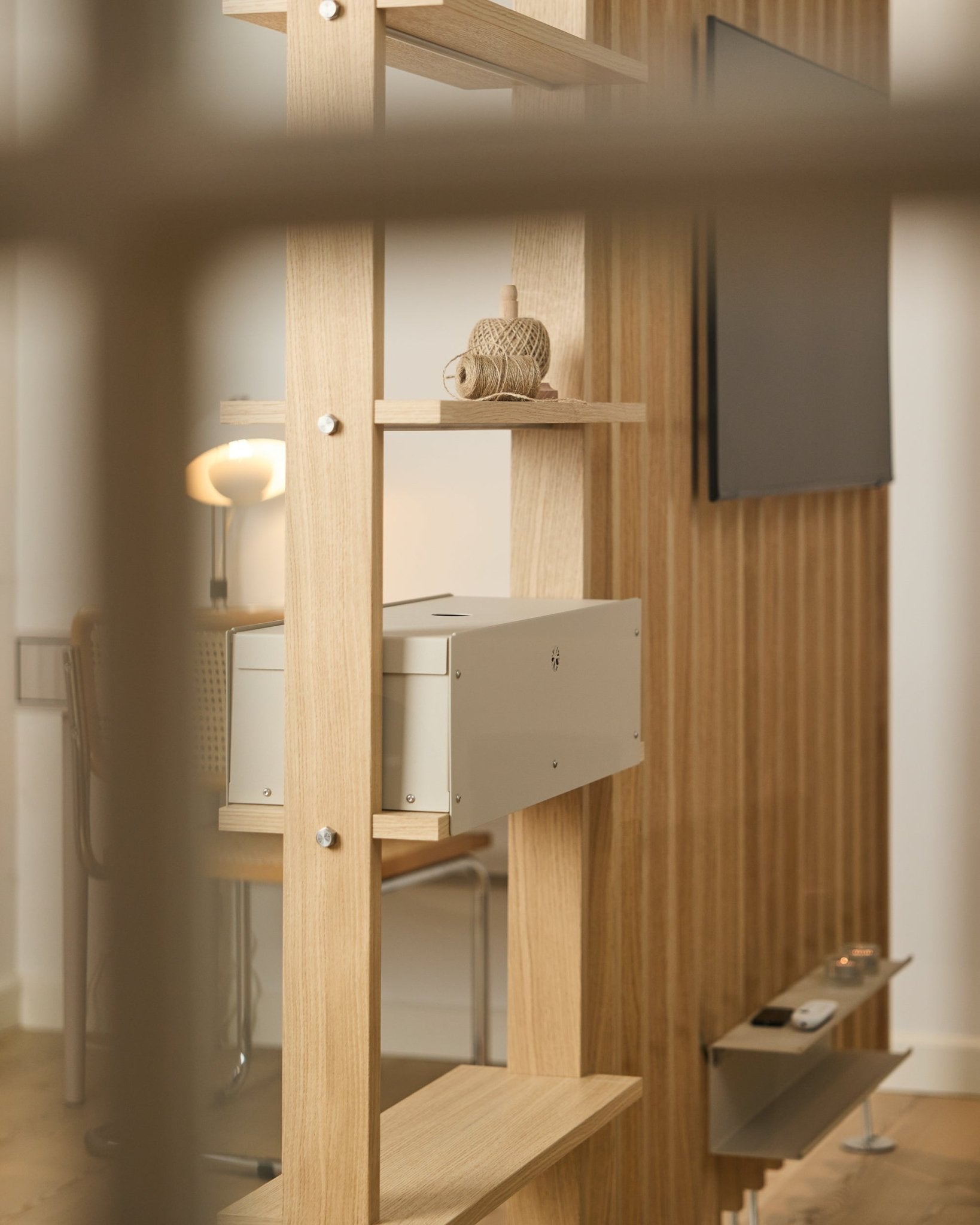 Et lunt rom med stol, lampe og TV har hyllen Nell | Metal Box / BM2 fra WoodUpp, utført i beige, med minimalistisk nordisk interiør.