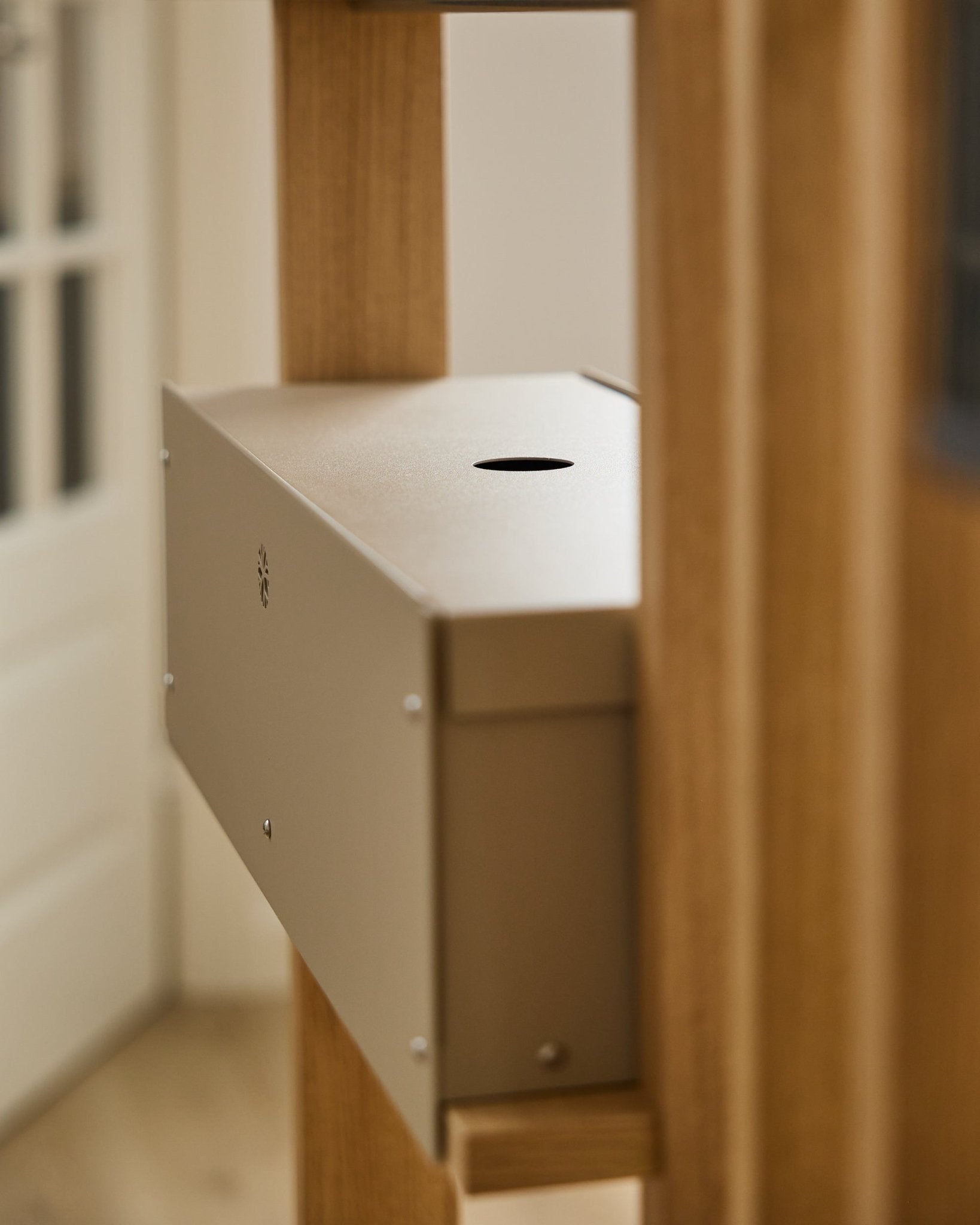 Nell | Metal Box / BM2, Beige fra WoodUpp er et pulverlakkert steel-tilbehør fra CREATE-kolleksjonen, plassert mellom akustiske trepaneler ved en hvit dør.